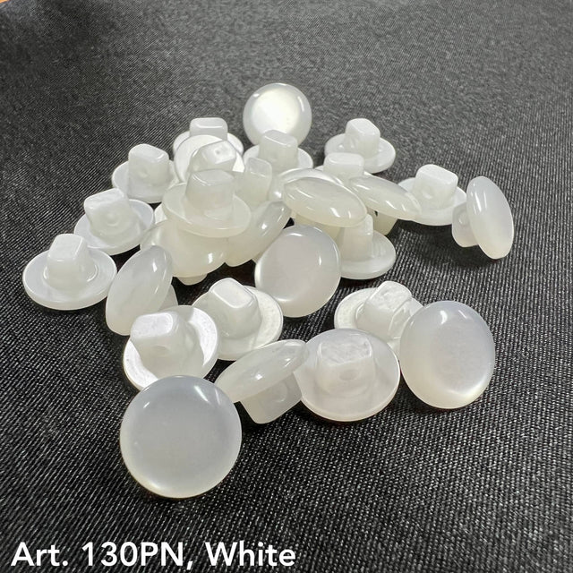 Glossy white traditional shank buttons scattered on dark fabric for clothing and upholstery