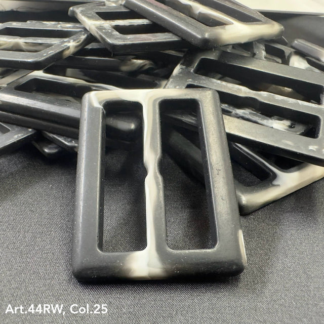 Close-up of fashion buckles for garments in various shades of brown arranged on dark fabric