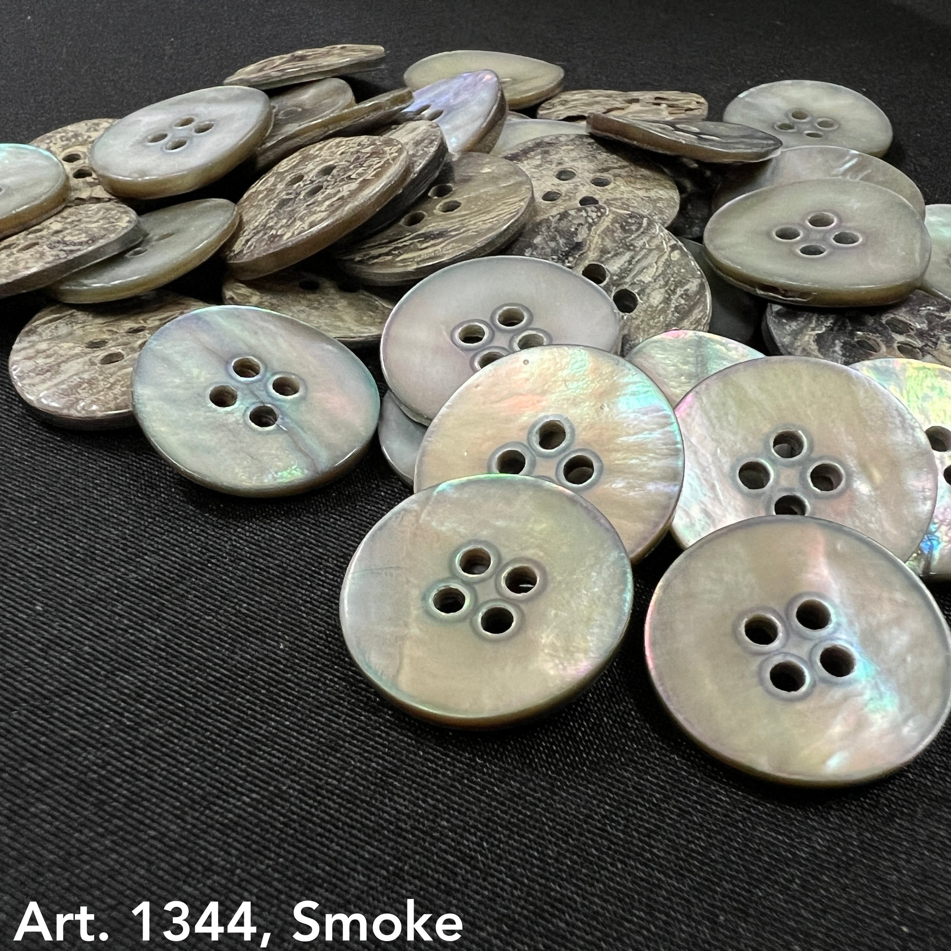 Akoya smoke buttons by Buttonology Inc with a shiny, iridescent finish on a black fabric background