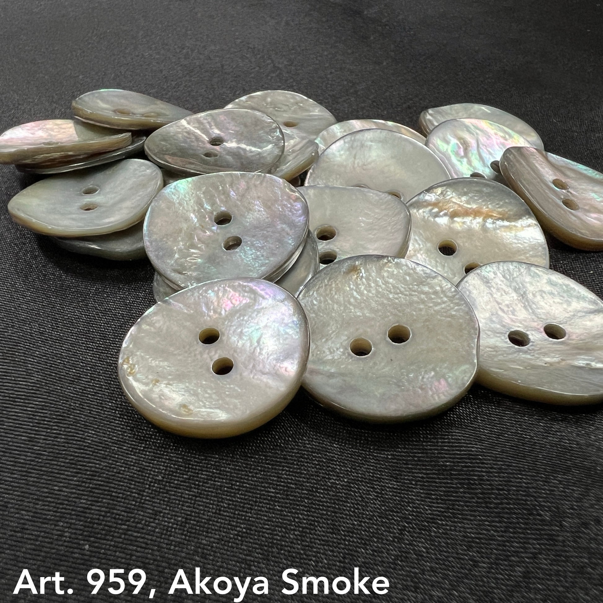 Akoya smoke buttons by Buttonology Inc with a pearlescent finish and two holes on black fabric