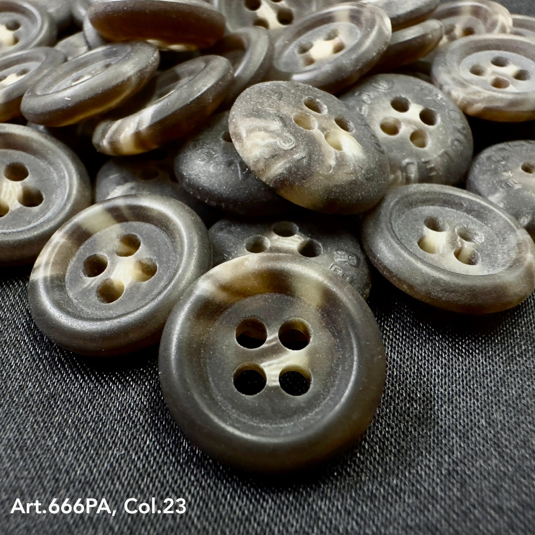 Close-up of Buttonology Inc recycled paper buttons in gray and brown tones with four holes