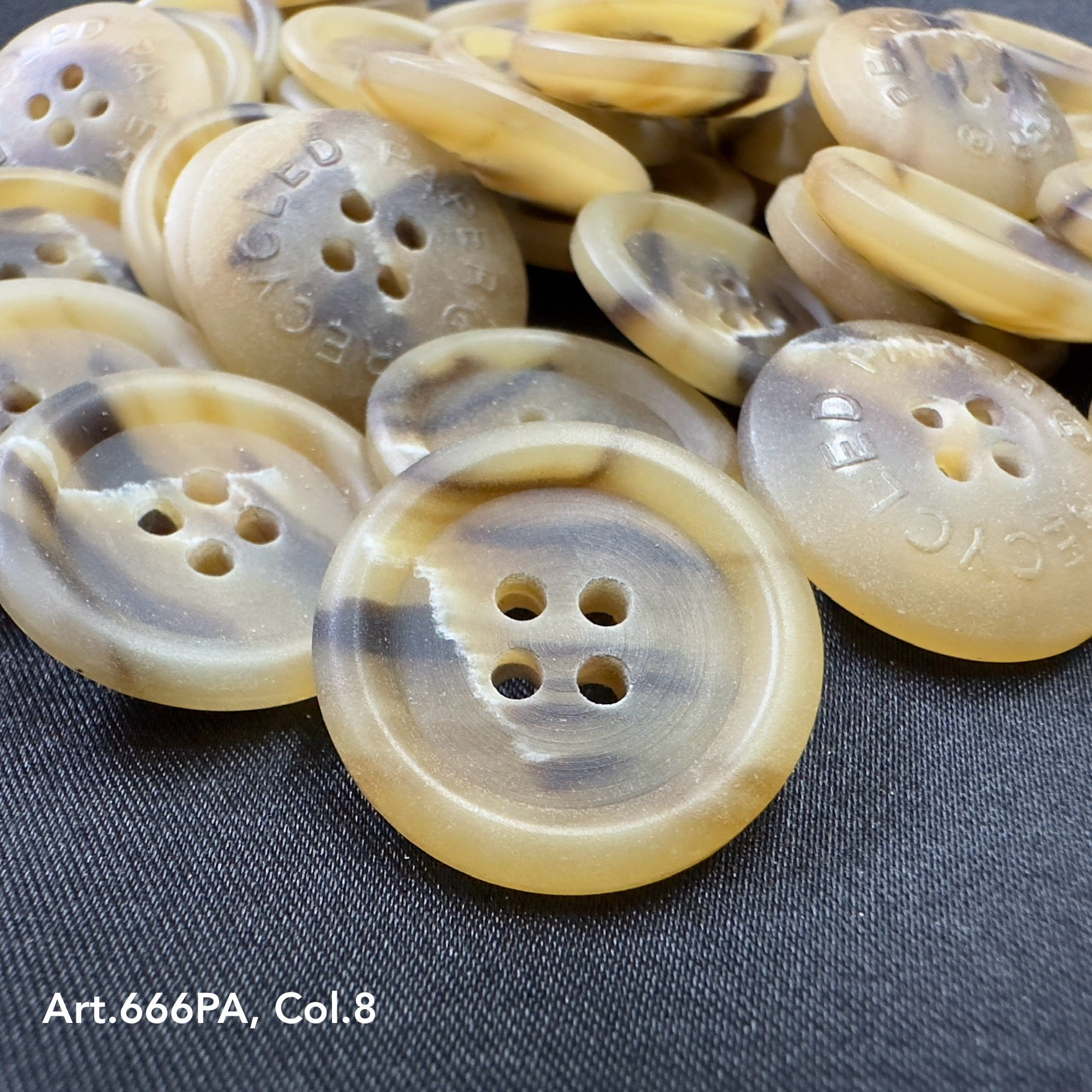 Recycled paper buttons by Buttonology Inc beige and brown with four holes on black fabric background