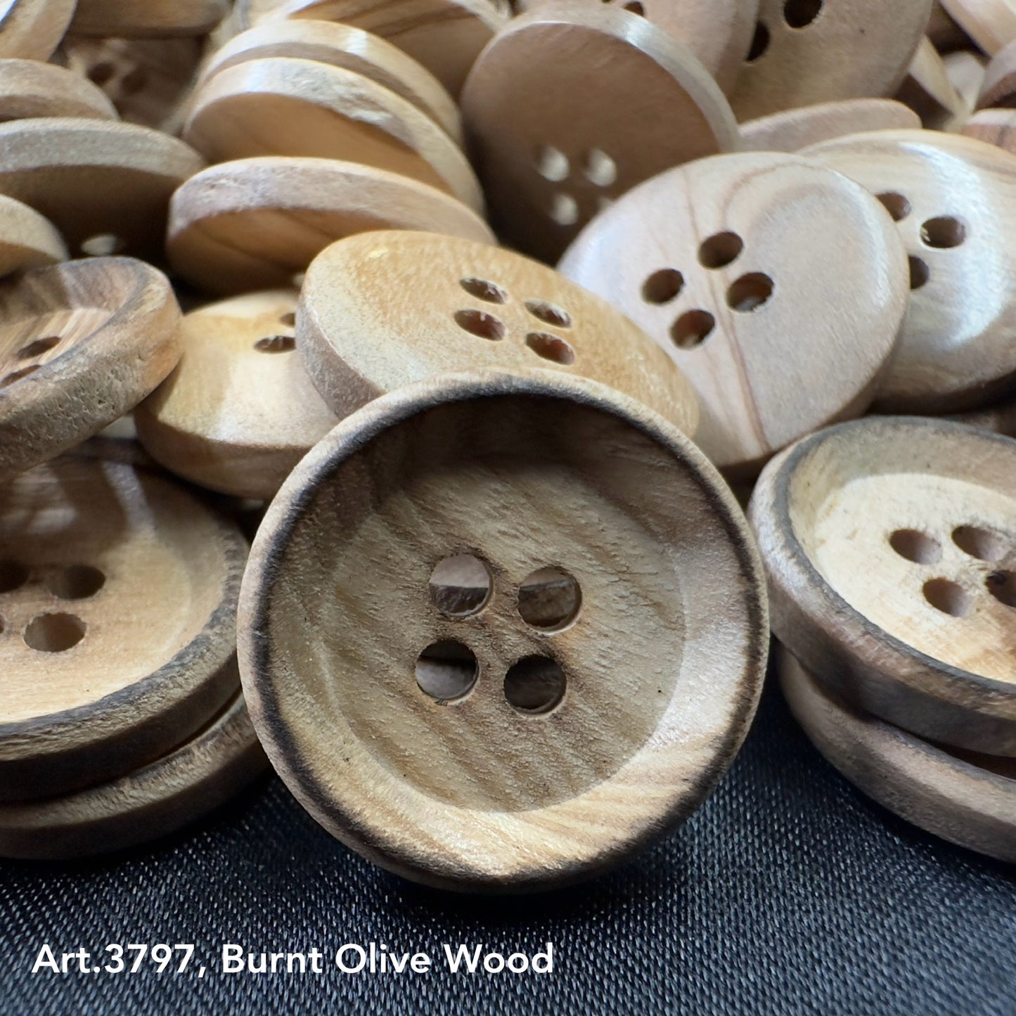 Close-up of burnt olive wood buttons with four holes, natural wood grain by Buttonology Inc