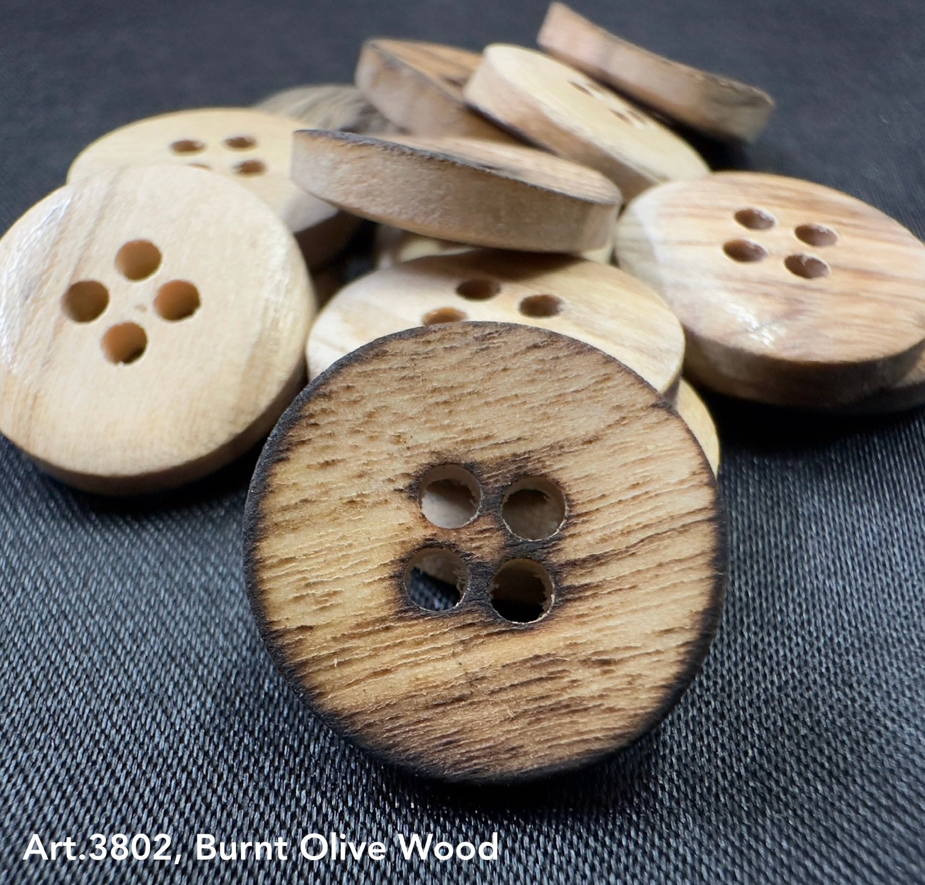 Burnt olivewood buttons by Buttonology Inc with a natural charred edge and four holes
