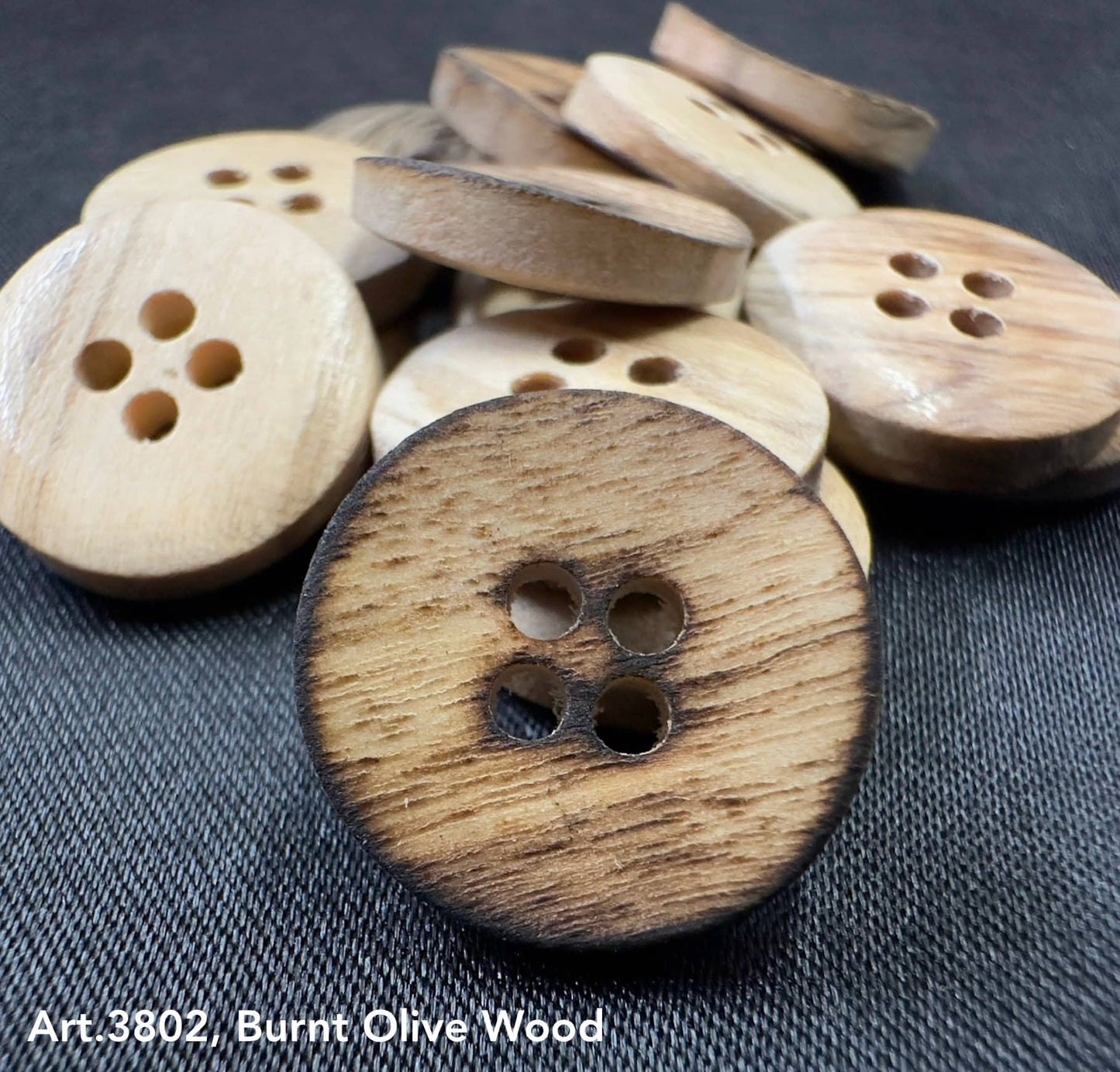 Burnt olivewood buttons by Buttonology Inc with a natural charred edge and four holes