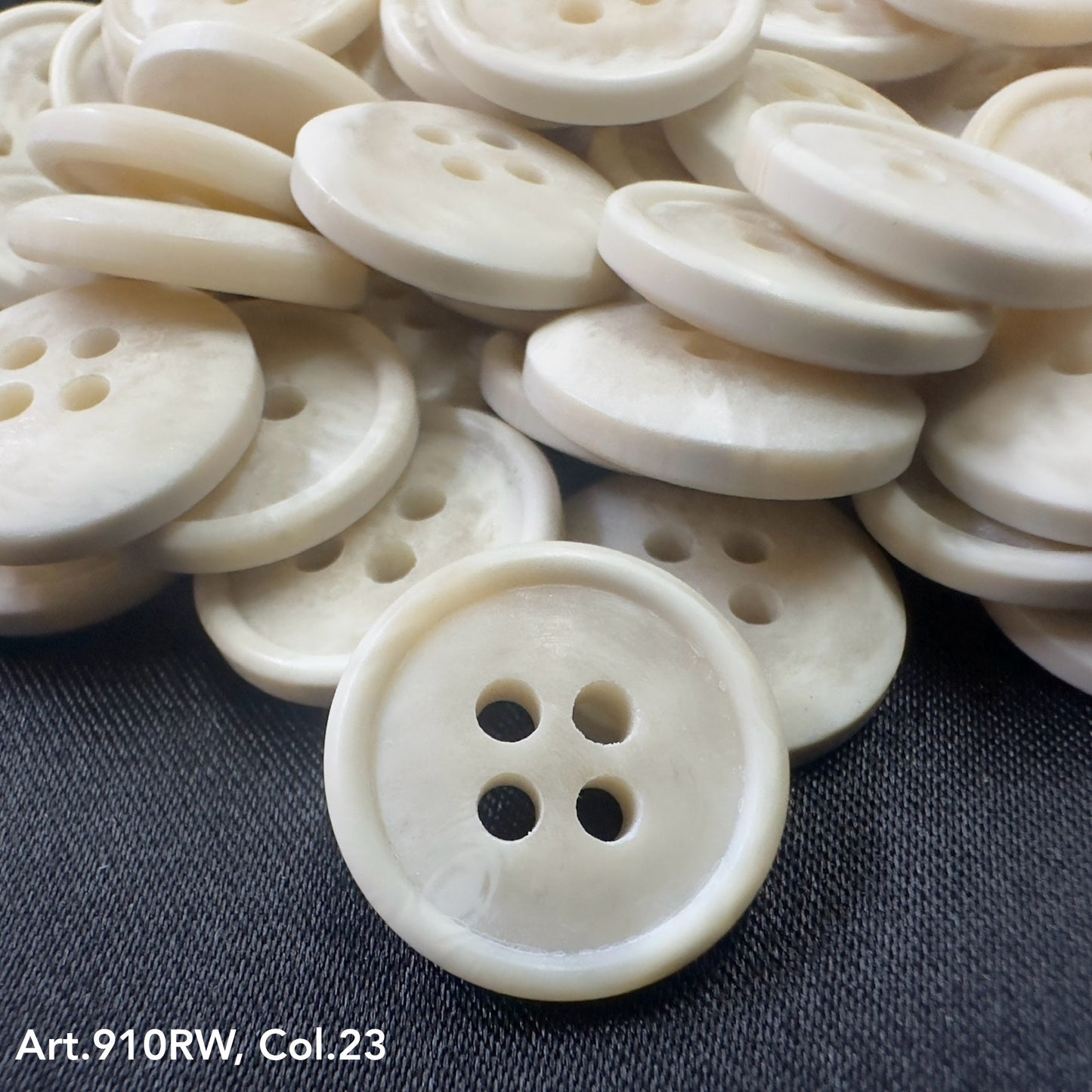 Buttonology Inc white four hole round buttons stacked on dark fabric coat buttons for sewing