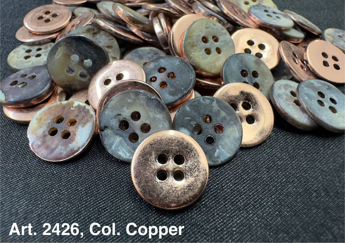 Buttonology Inc copper shell garment buttons four hole aged patina finish on dark woven fabric background