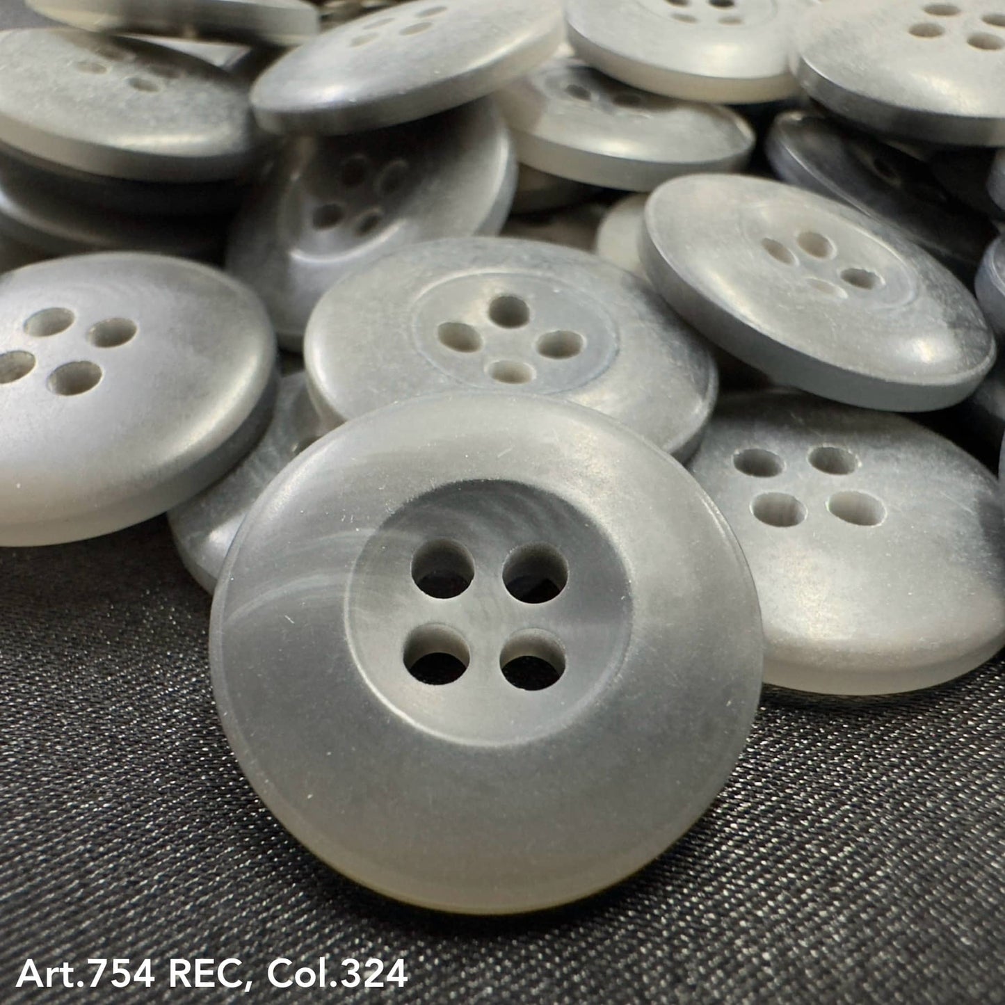 Gray plastic buttons with four holes showing custom button designs by Buttonology Inc
