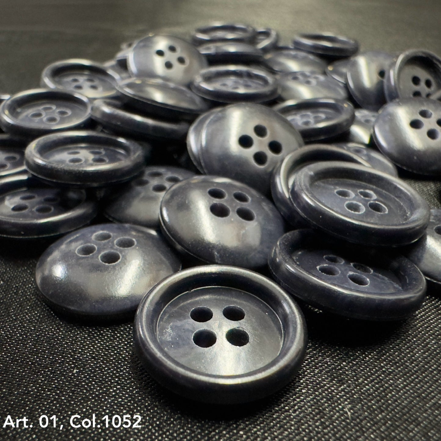 Pile of dark gray glossy four hole round buttons for shirts by Buttonology Inc premium shirt buttons for sewing