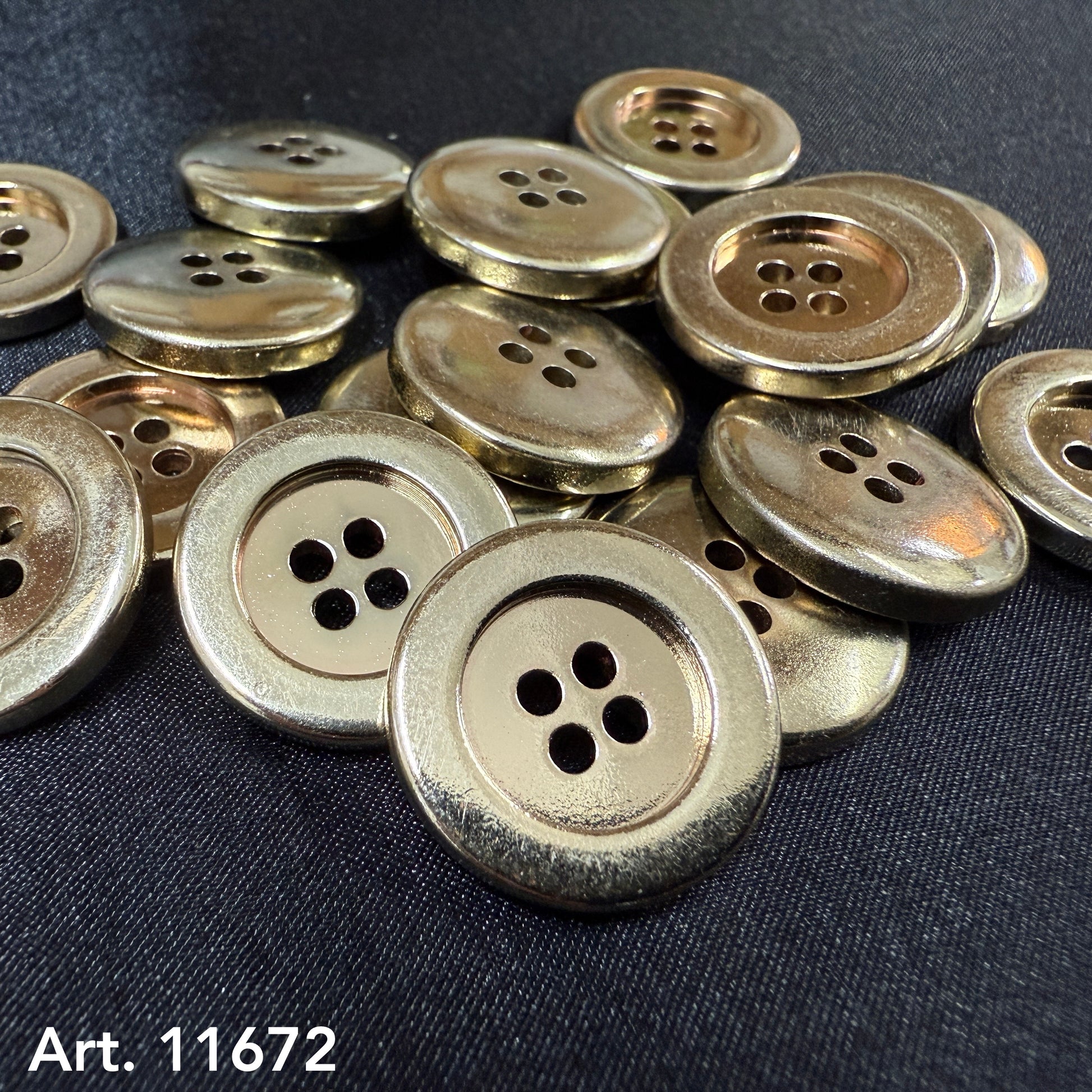 Close up pile of premium gold garment buttons four hole metal buttons on black fabric Buttonology Inc