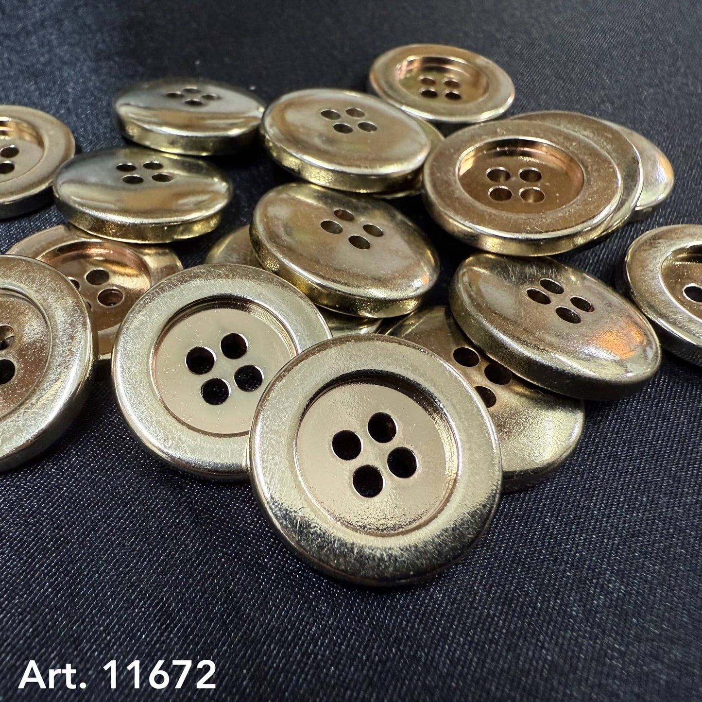 Close up pile of premium gold garment buttons four hole metal buttons on black fabric Buttonology Inc