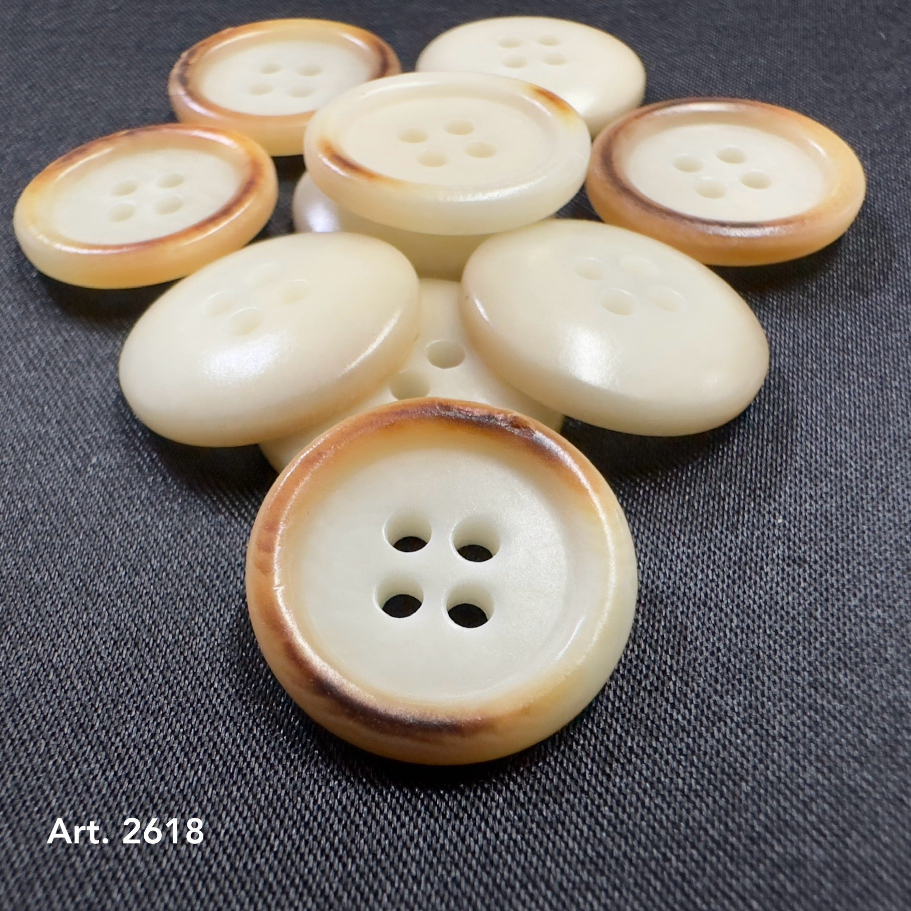 Burnt corozo button for shirts by Buttonology Inc with four holes on dark fabric background