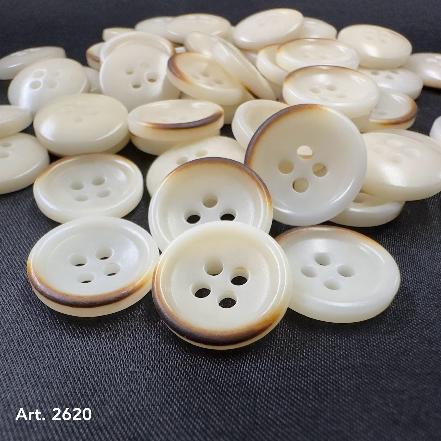 Burnt corozo buttons by Buttonology Inc with a natural brown edge on creamy white surface