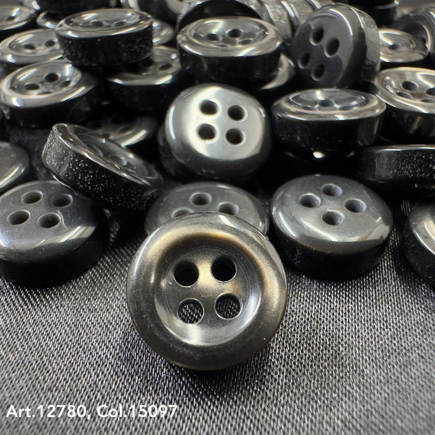 Black four-hole buttons on fabric showcasing Buttonology quality button supply from Buttonology Inc