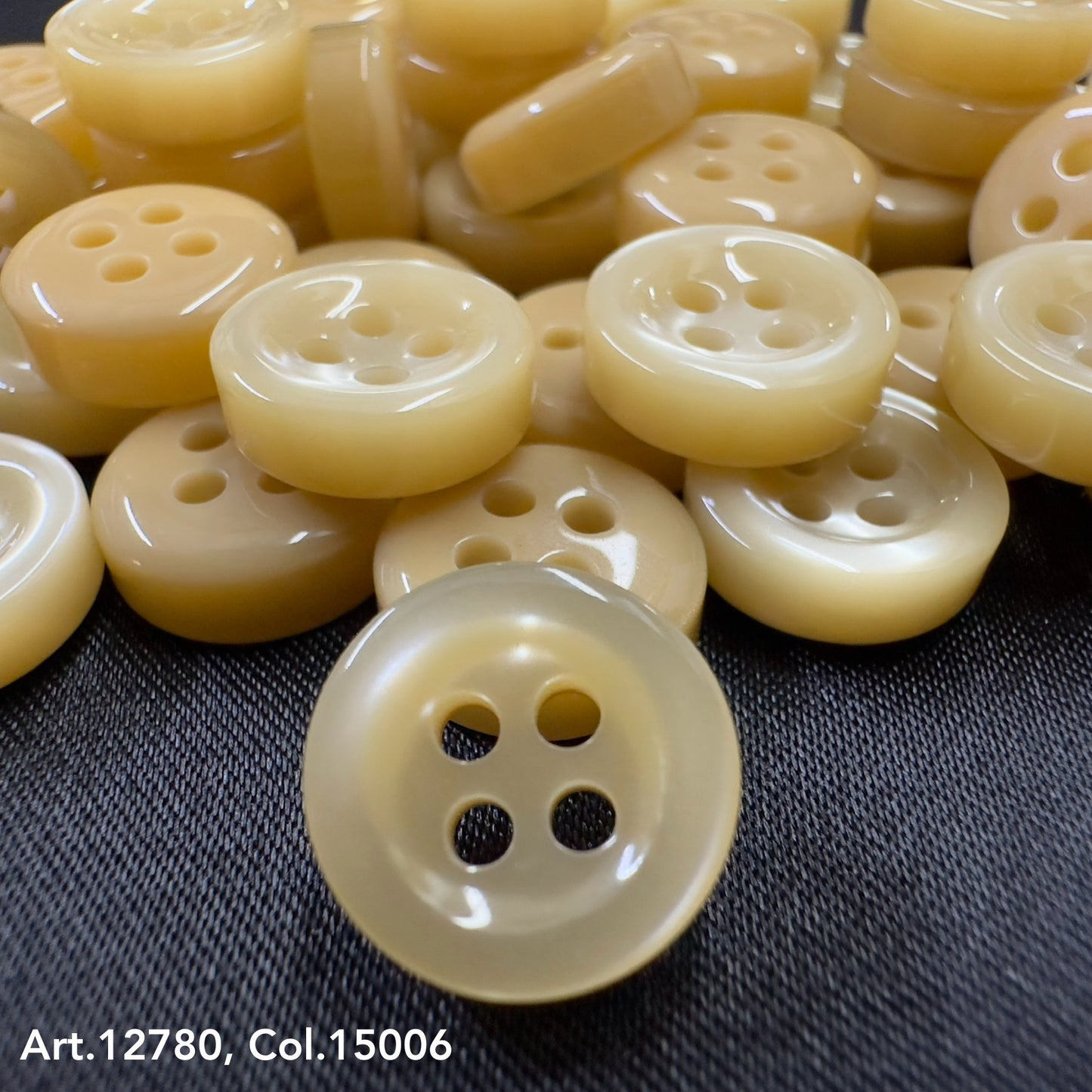 Close-up of Buttonology quality button supply beige buttons with four holes on black fabric background