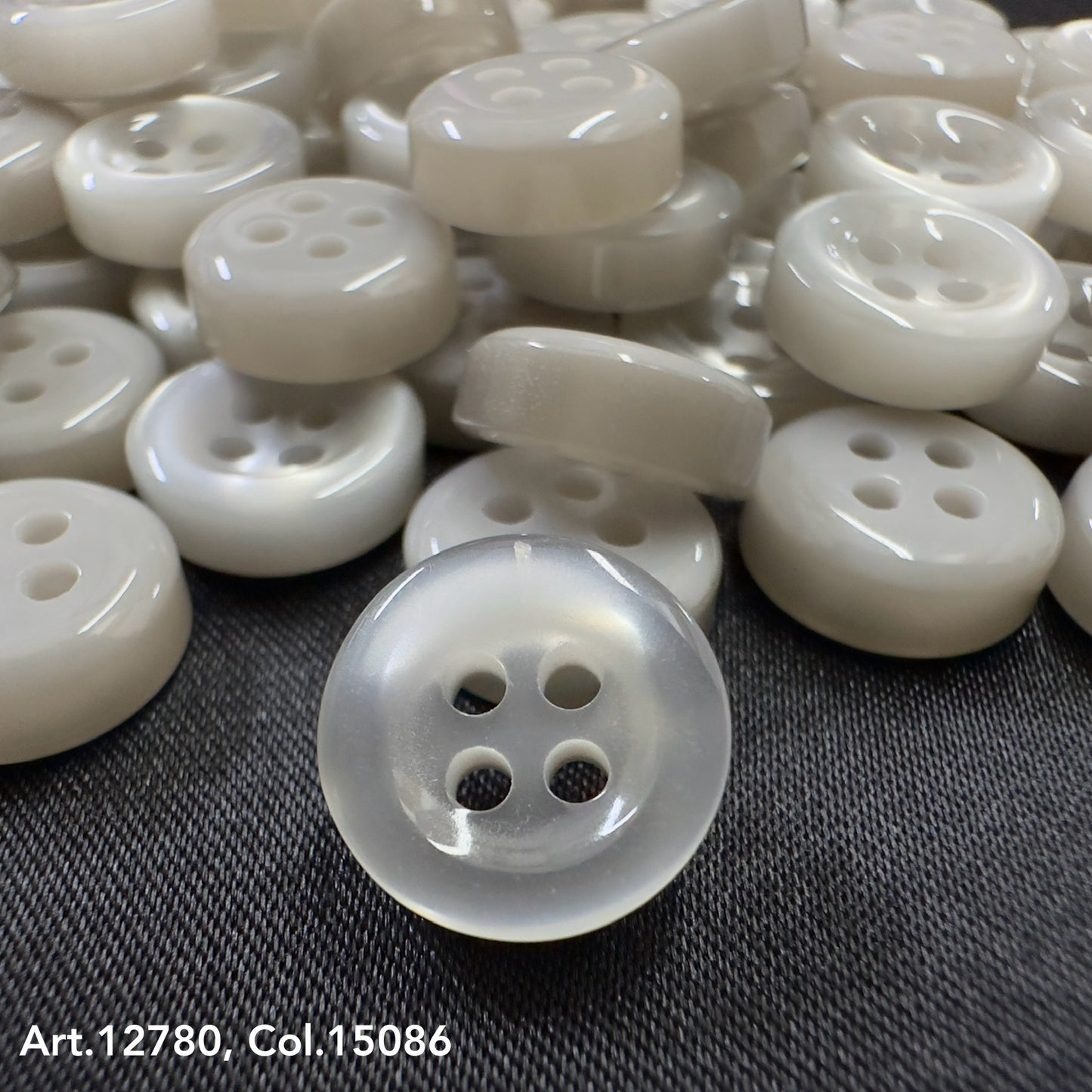 Buttonology quality button supply white four-hole buttons on black fabric surface