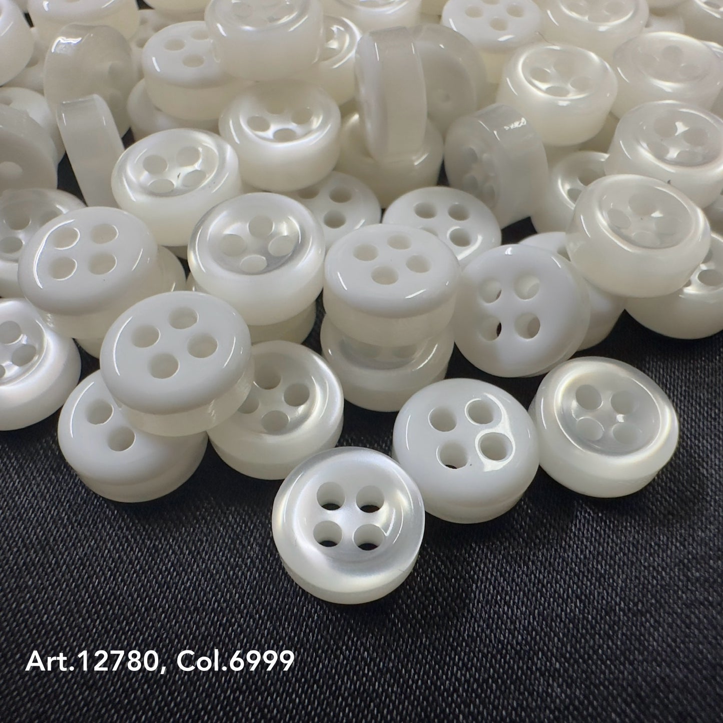 Buttonology quality button supply white four-hole buttons on black fabric background