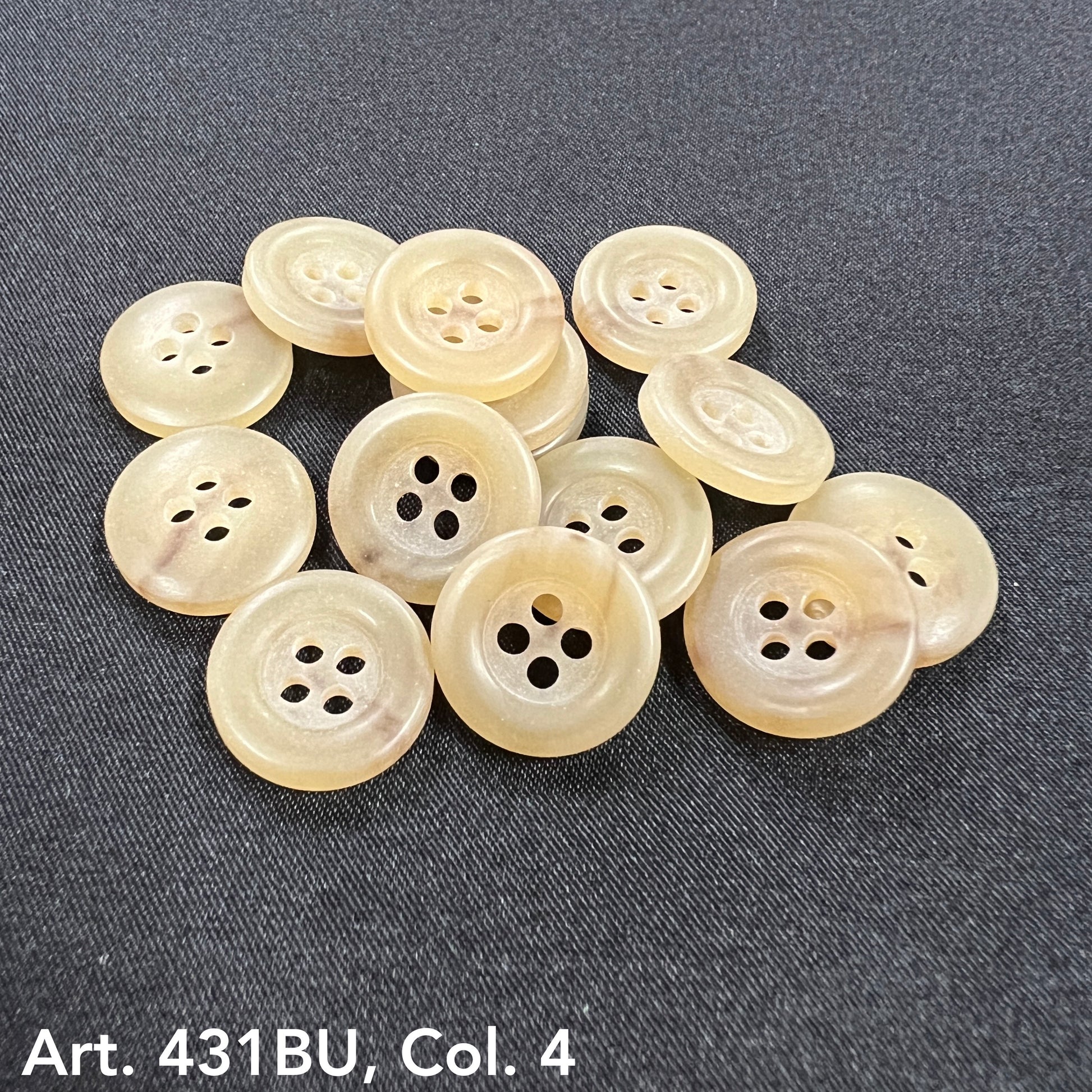 Set of beige round buttons for sale with four holes from Buttonology Inc on black fabric