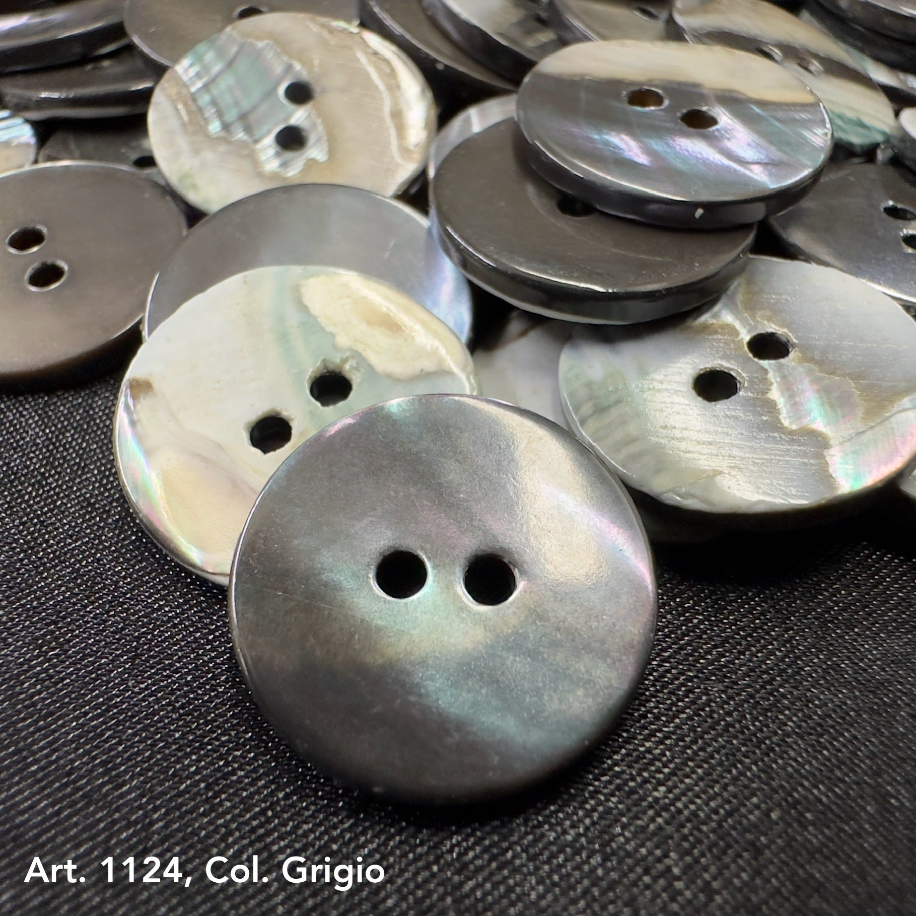 Gray shell buttons from Buttonology Inc for DIY shell button projects on black fabric background