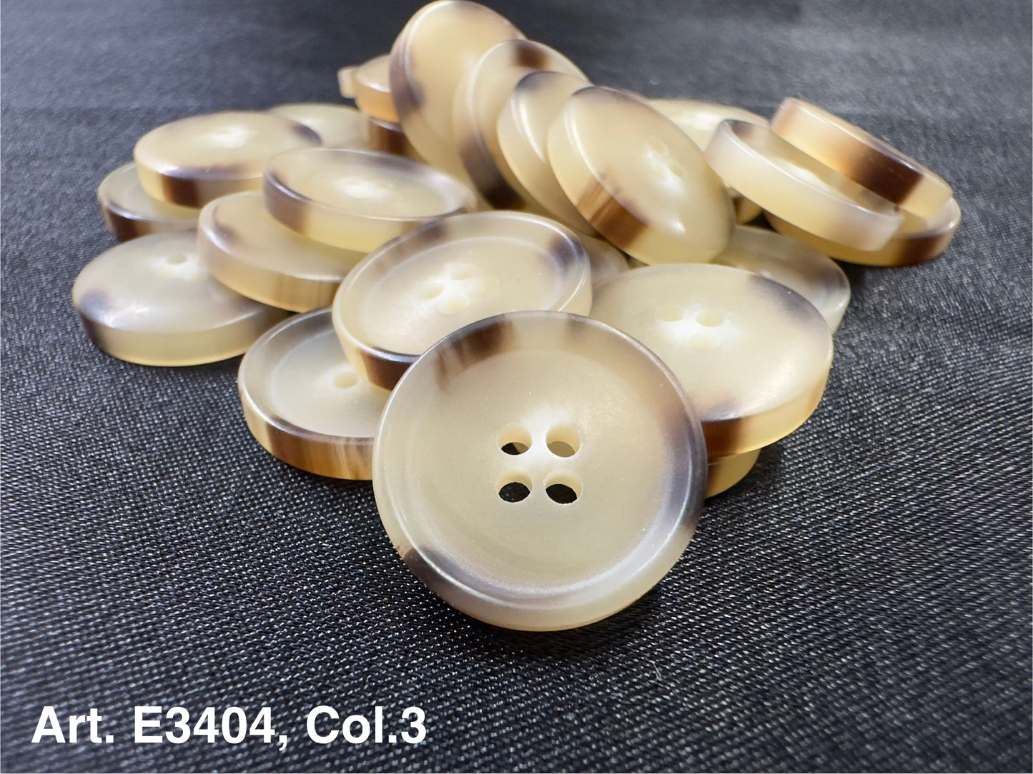 Buttonology Inc beige round buttons with brown rim stacked on dark fabric four hole sewing buttons