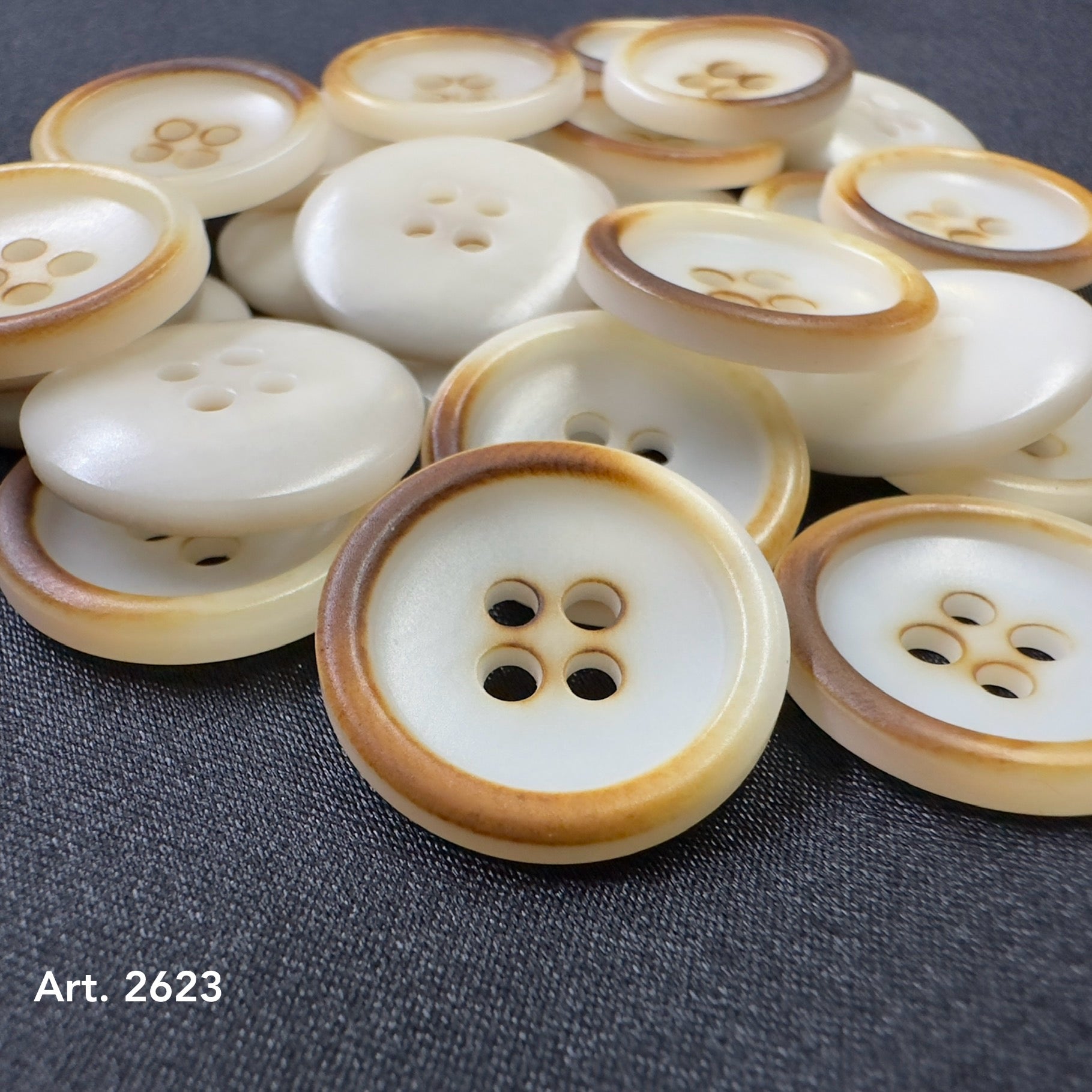 Eco-Friendly Burnt corozo buttons by Buttonology Inc with natural brown edges and four holes on dark fabric