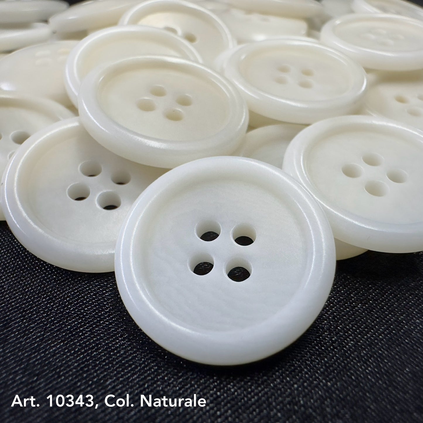 Close-up of white eco-friendly clothing buttons with four holes on black fabric background