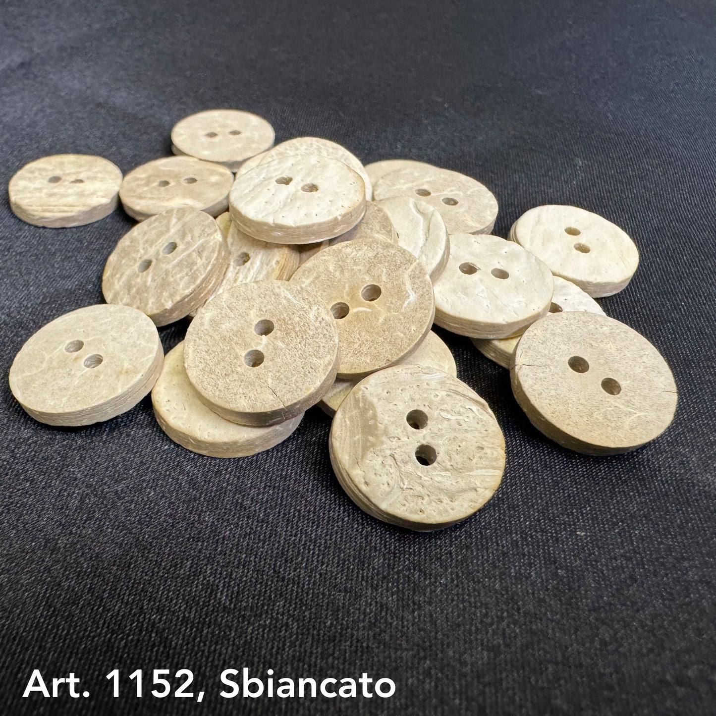 Eco-friendly coconut buttons by Buttonology Inc in natural beige color with two holes on black fabric