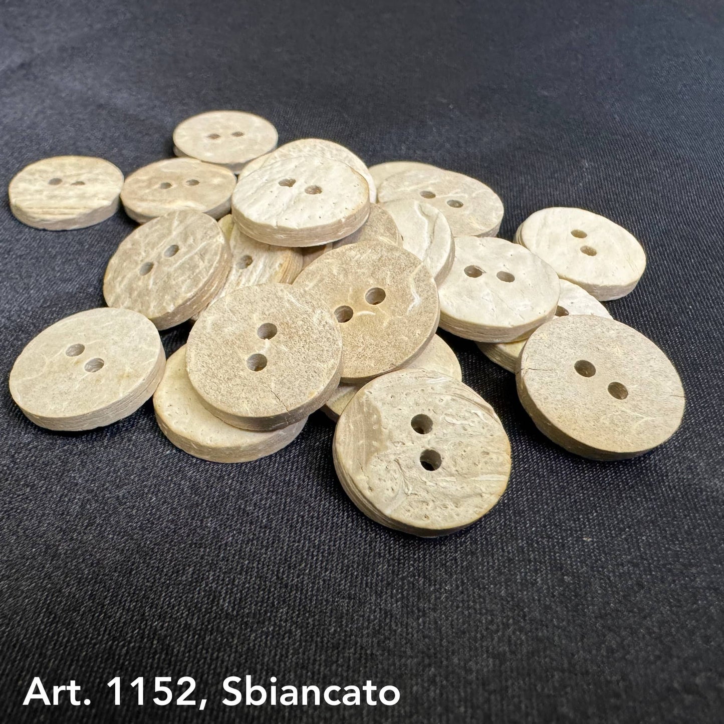 Eco-friendly coconut buttons by Buttonology Inc in natural beige color with two holes on black fabric