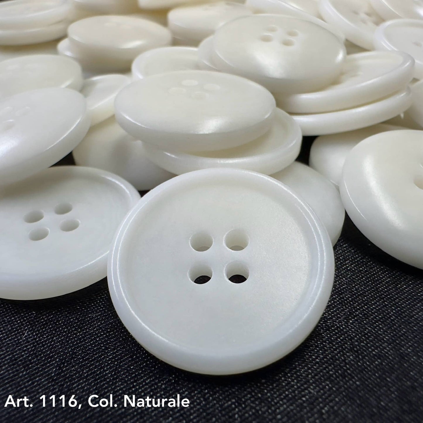 White eco-friendly corozo buttons with four holes from Buttonology Inc on black background