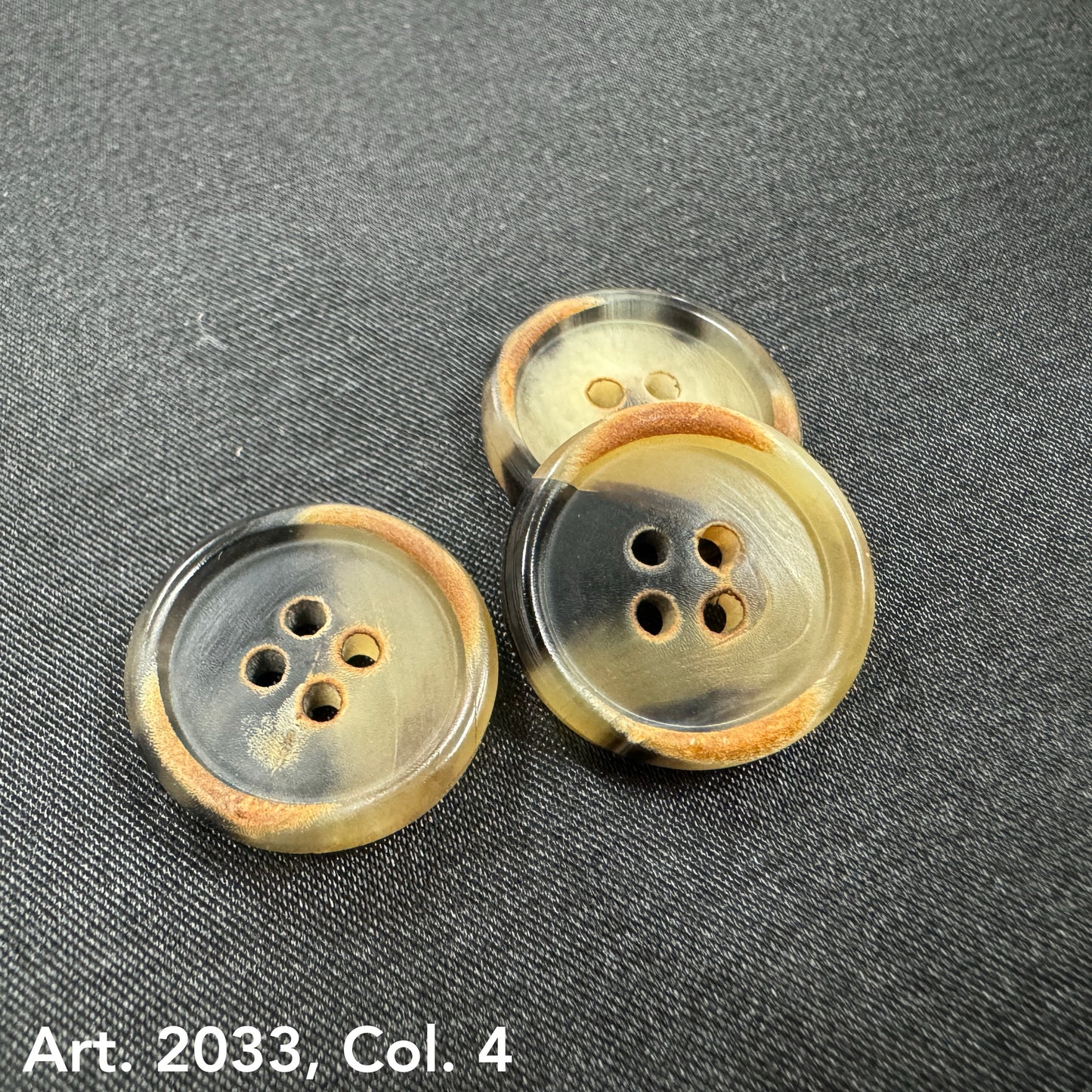 Eco-friendly horn buttons by Buttonology Inc with natural brown and black tones on fabric background