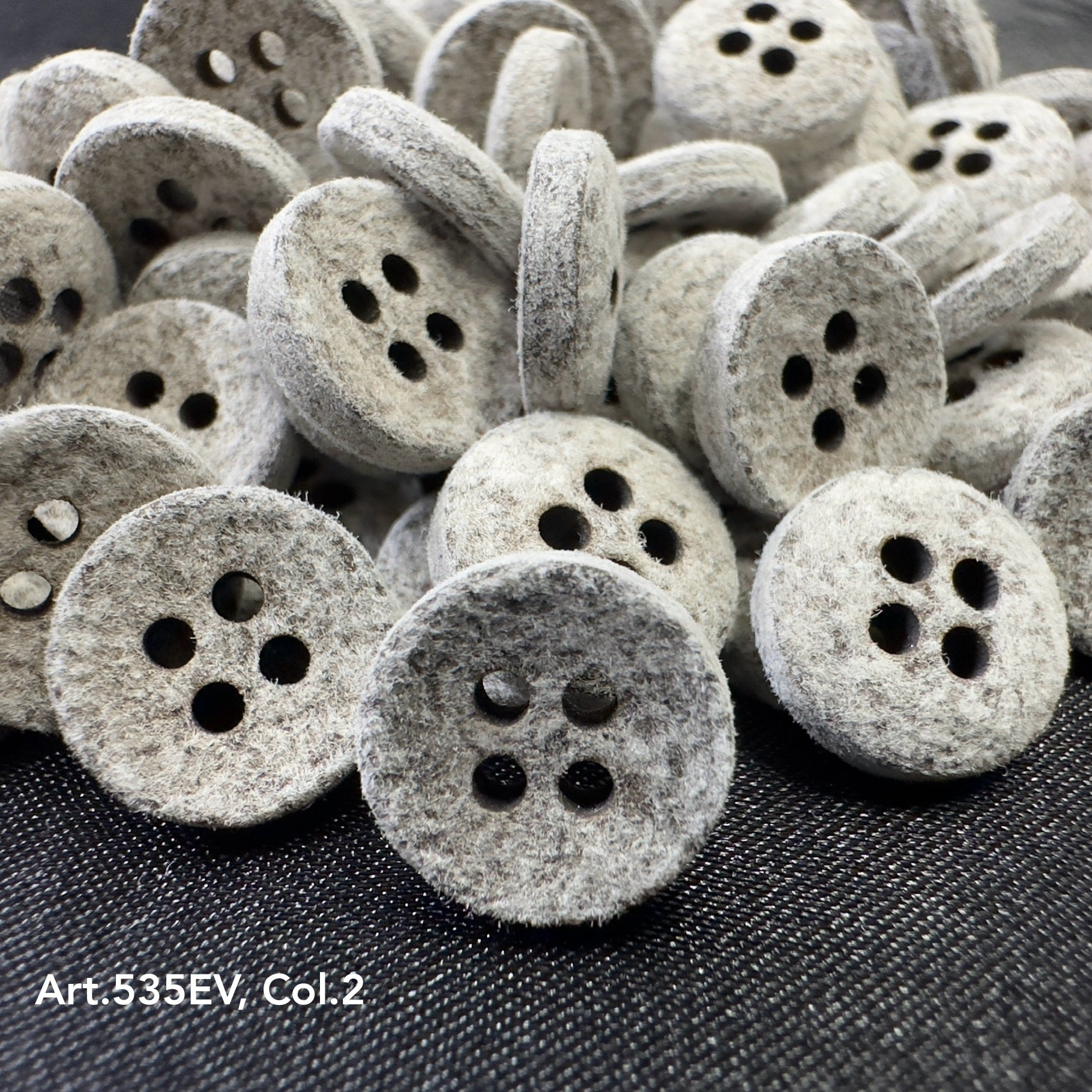 Eco-Velvet textured four-hole buttons by Buttonology Inc in a close-up pile on dark fabric