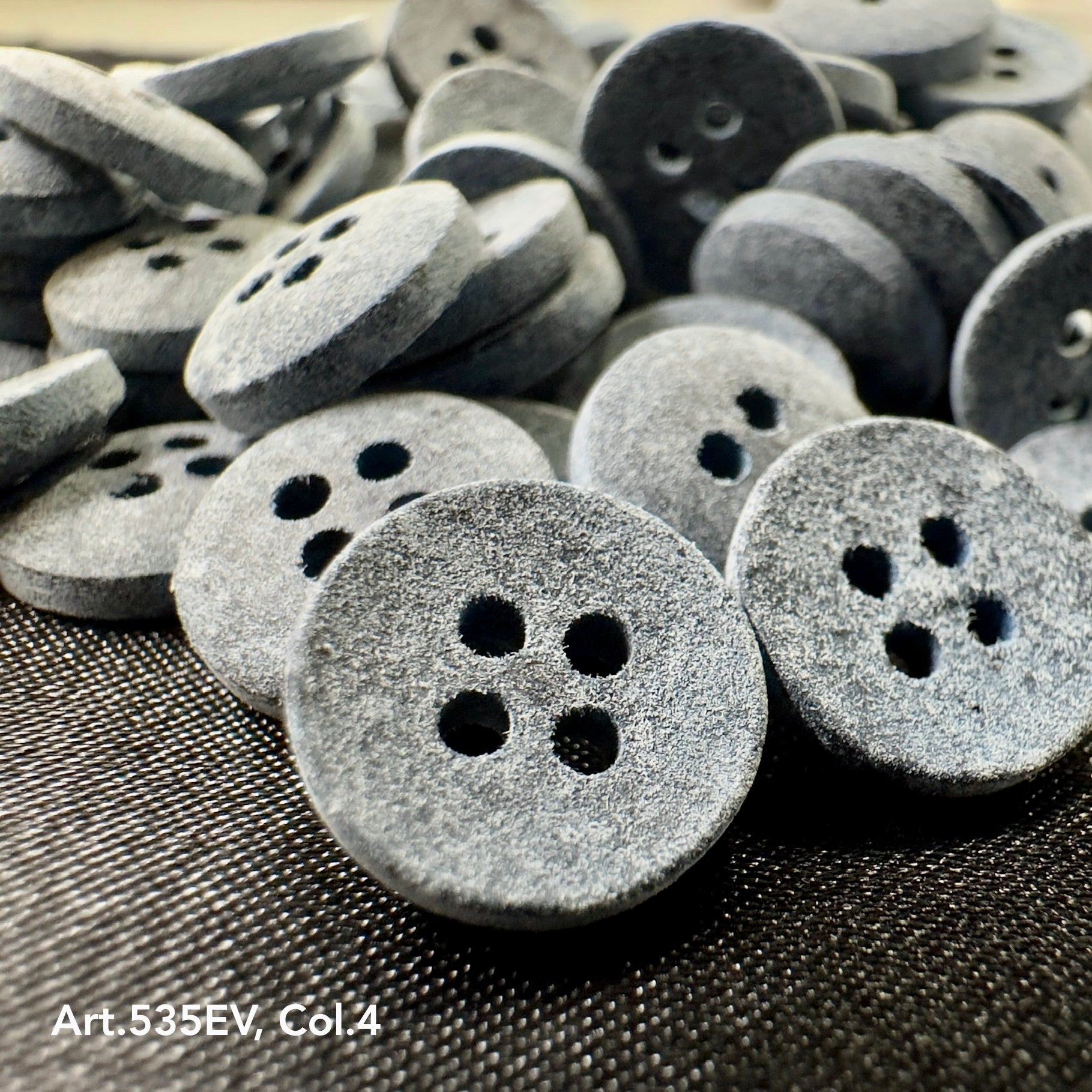 Eco-Velvet textured round gray buttons with four holes by Buttonology Inc displayed on black fabric