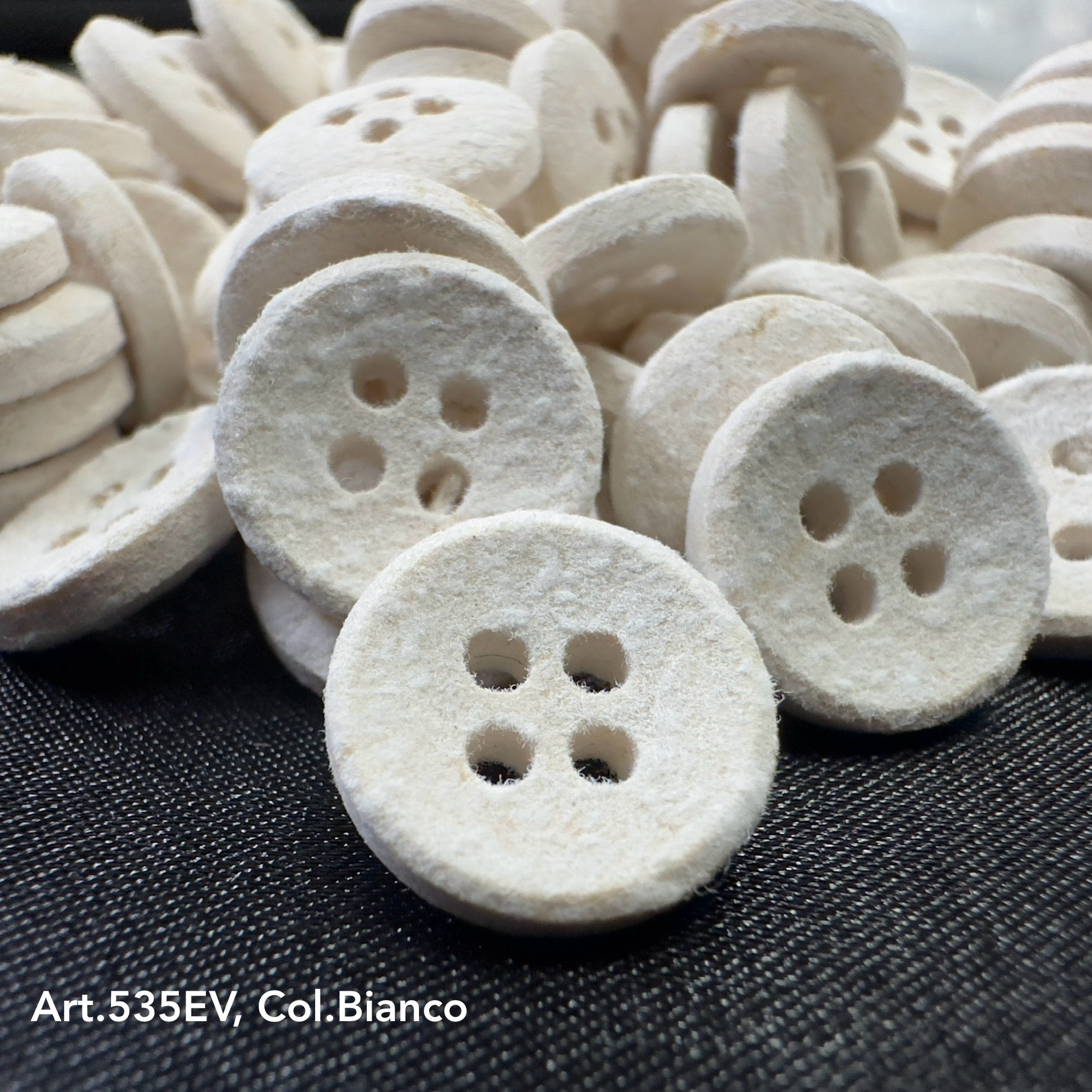 Eco-Velvet white textured buttons with four holes by Buttonology Inc on black fabric background