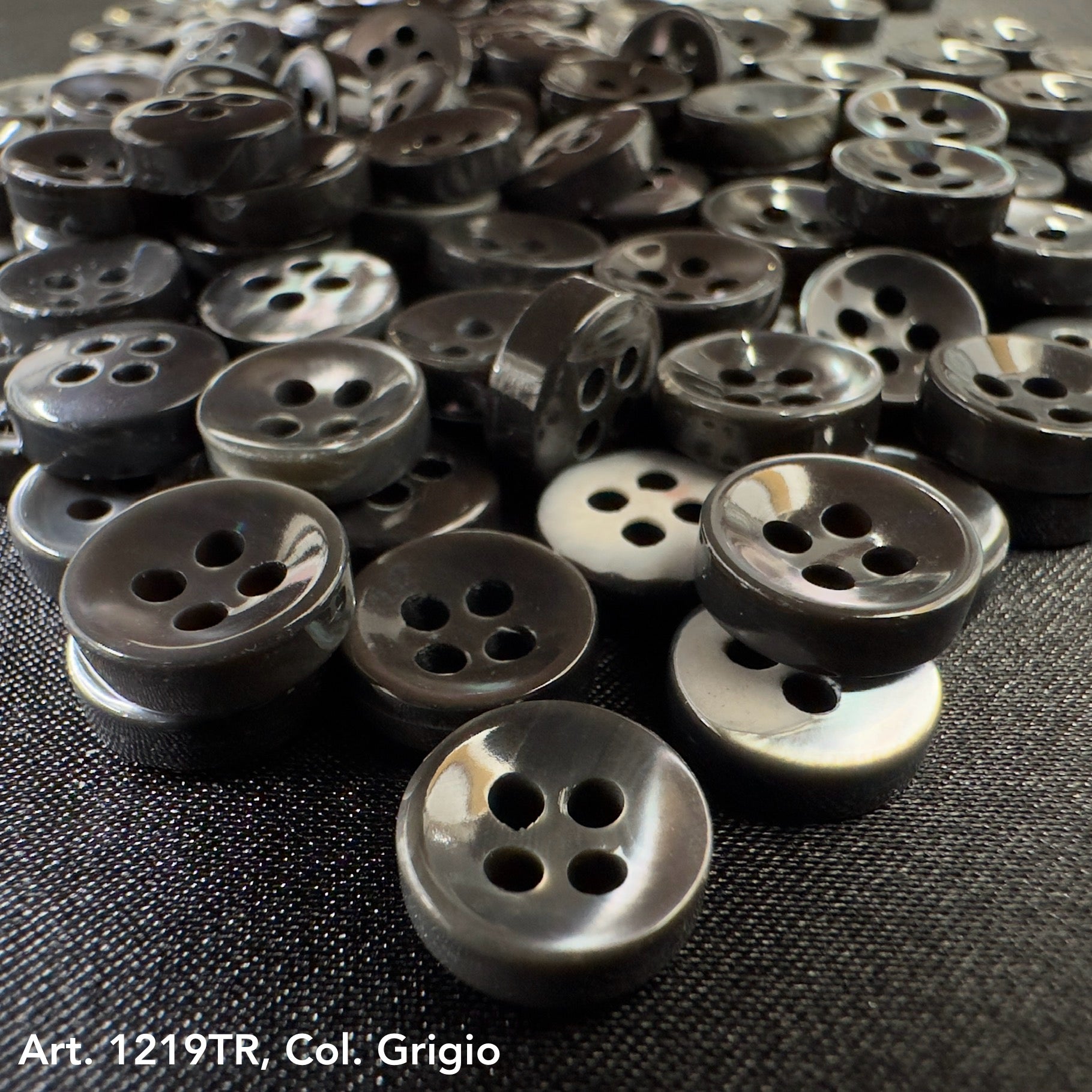 Buy decorative buttons online from Buttonology Inc featuring glossy black four-hole buttons on fabric background