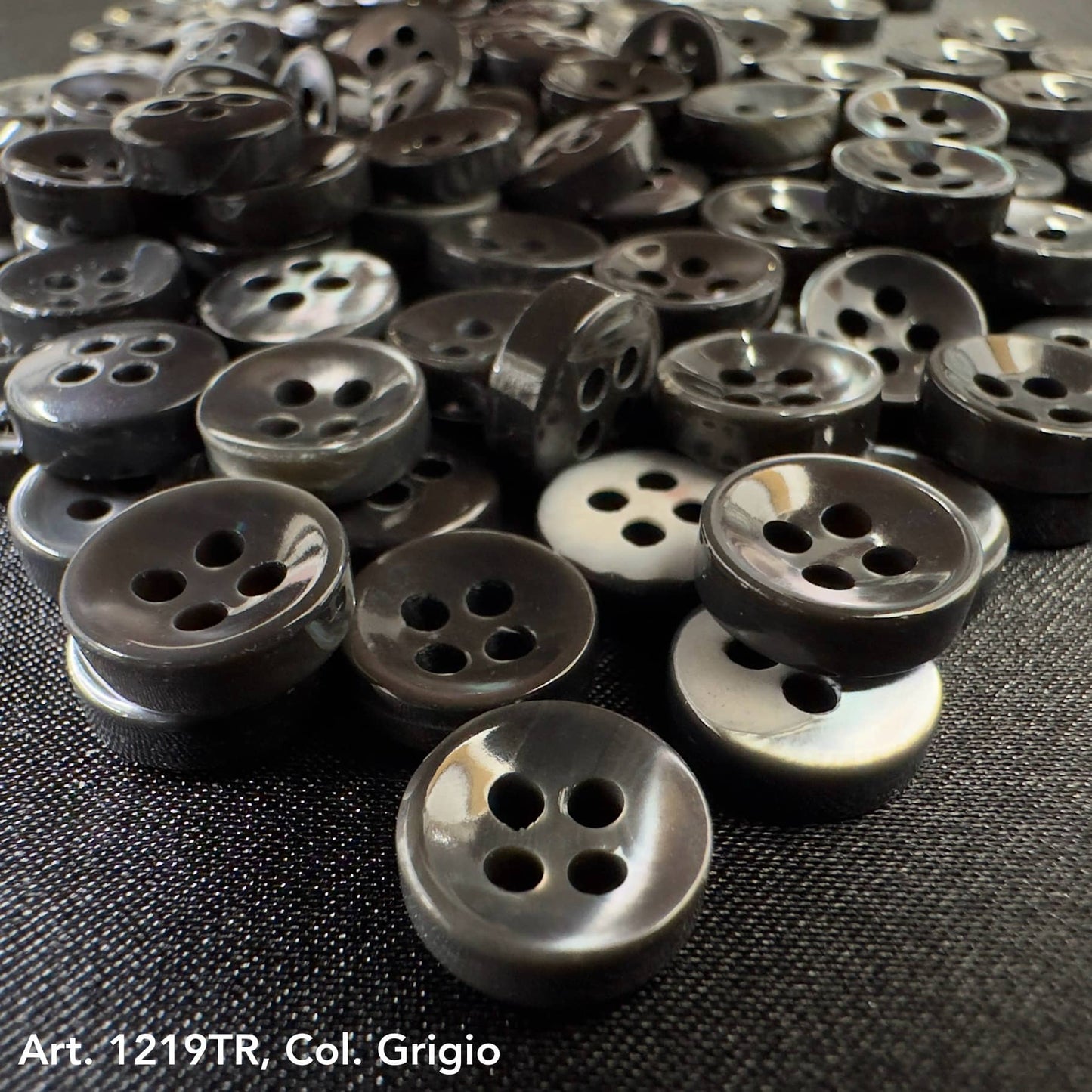 Buy decorative buttons online from Buttonology Inc featuring glossy black four-hole buttons on fabric background