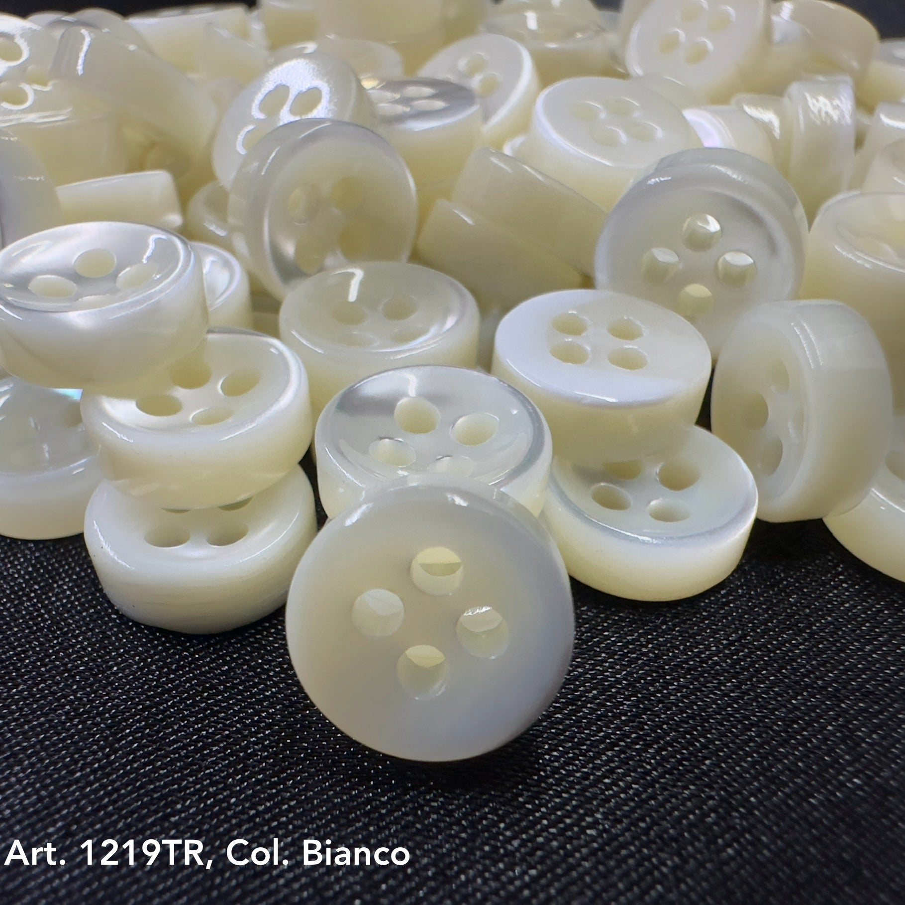 White decorative buttons with four holes on black fabric to buy decorative buttons online from Buttonology Inc