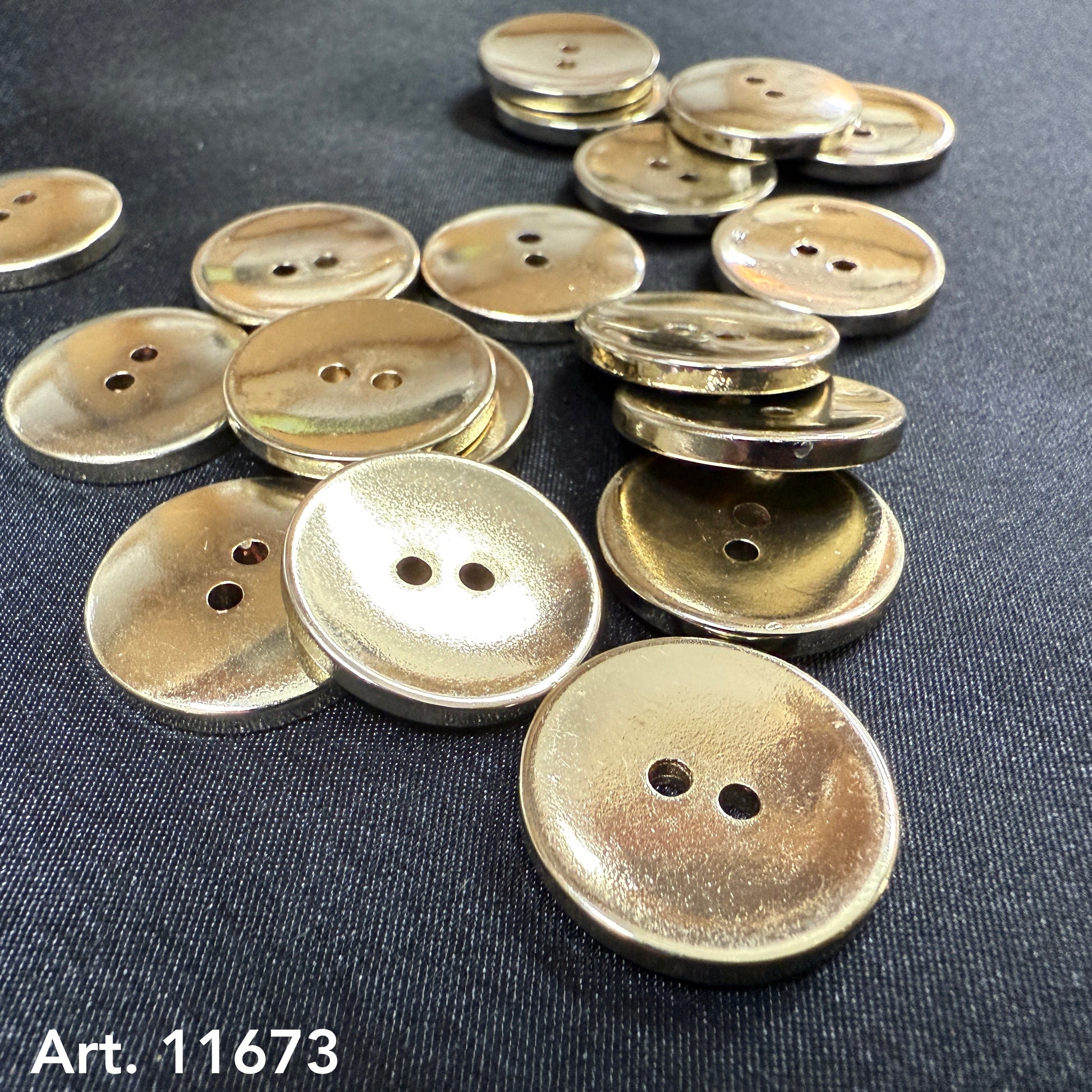 Gold metal buttons from Buttonology Inc scattered on a black fabric background