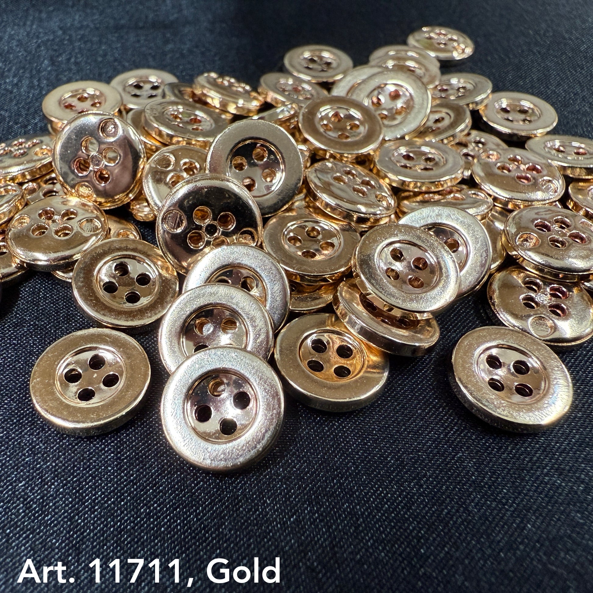 Gold sewing buttons from Buttonology Inc scattered on black fabric background