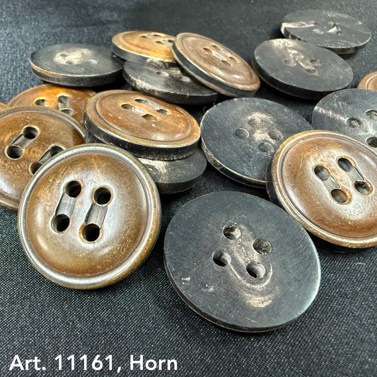 Large horn buttons for coats in brown and black from Buttonology Inc scattered on fabric