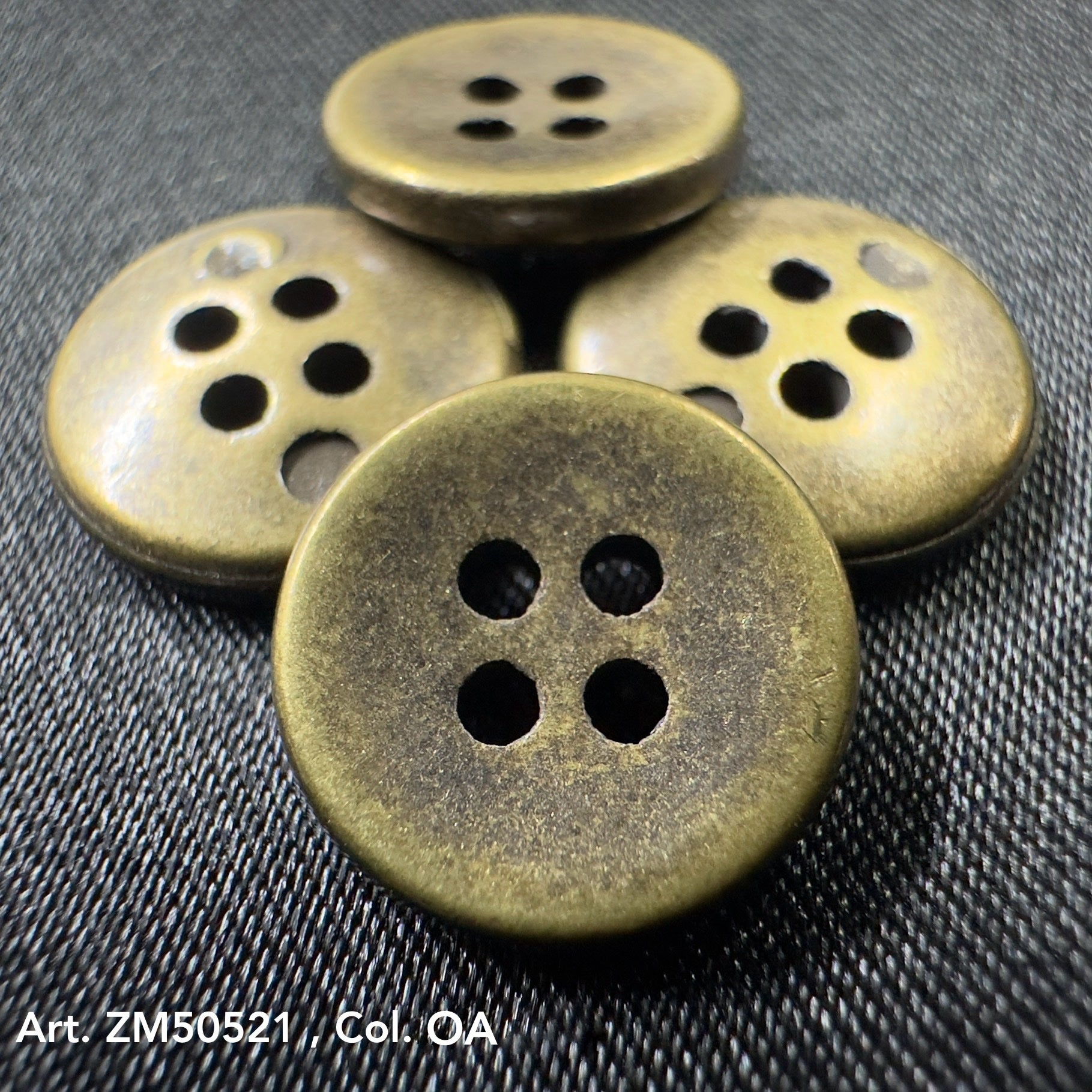 Antique brass metal buttons for clothes with four holes on textured fabric background