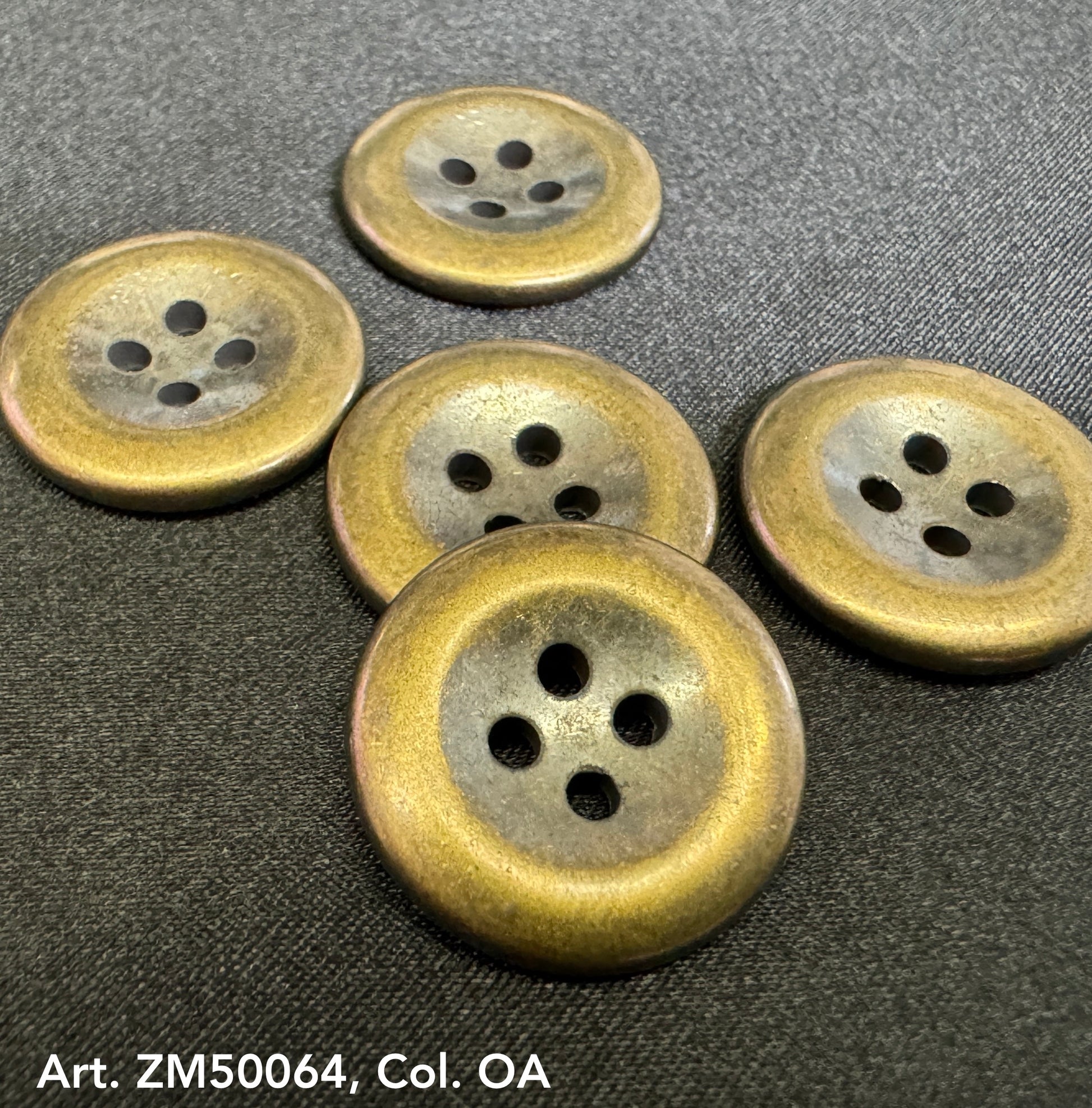 Set of five round metal buttons for clothing with a vintage brass finish on black fabric