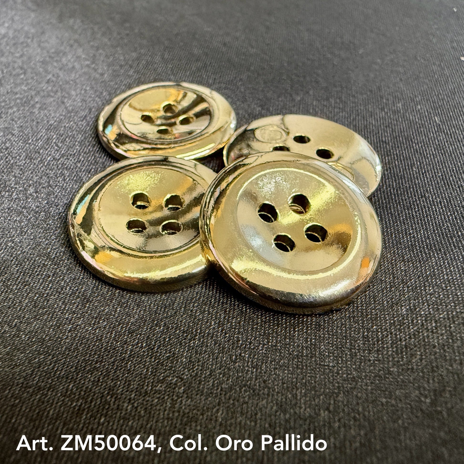 Shiny gold metal buttons for clothing with four holes arranged on black fabric background