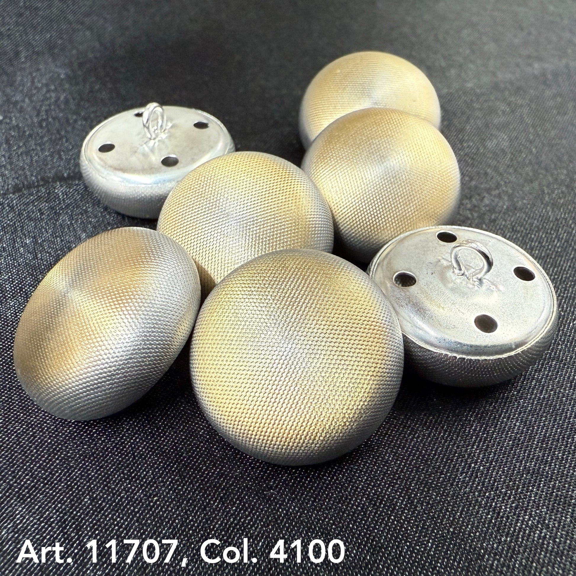 Set of metal dome buttons for coats with textured silver finish on dark fabric background