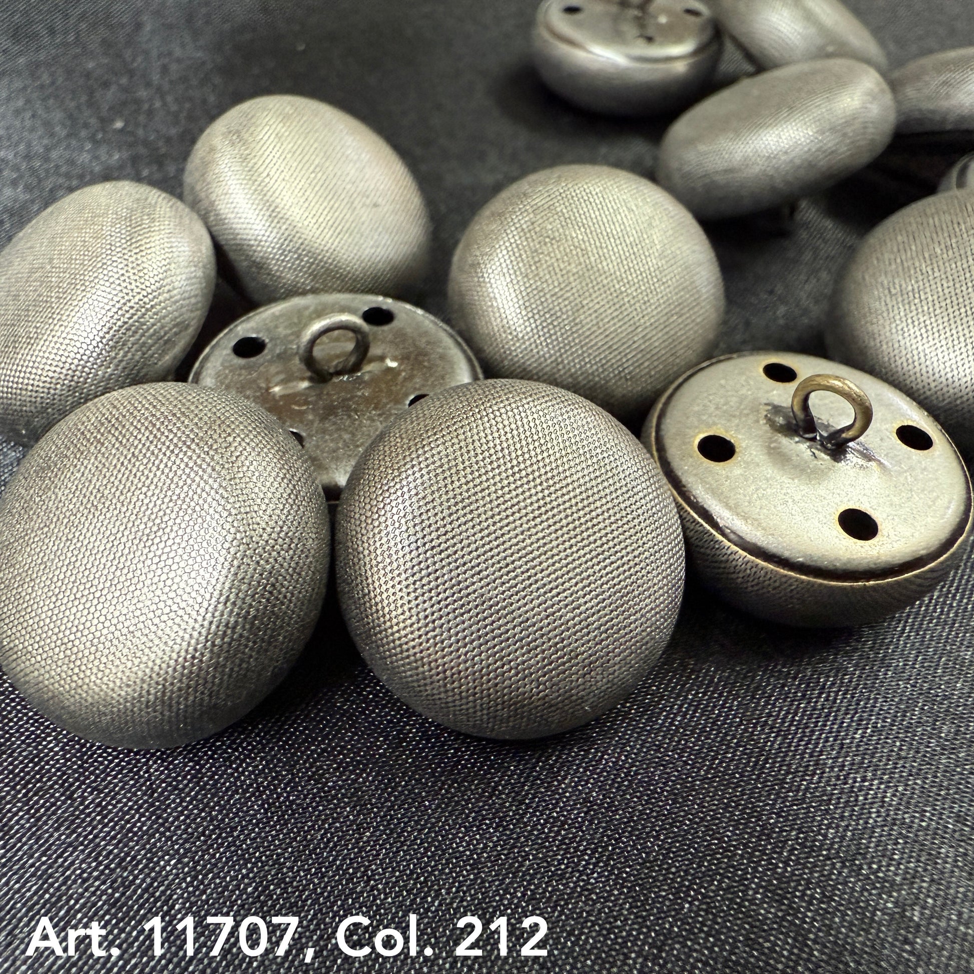Metal dome buttons for coats with textured silver finish from Buttonology Inc close-up on dark fabric