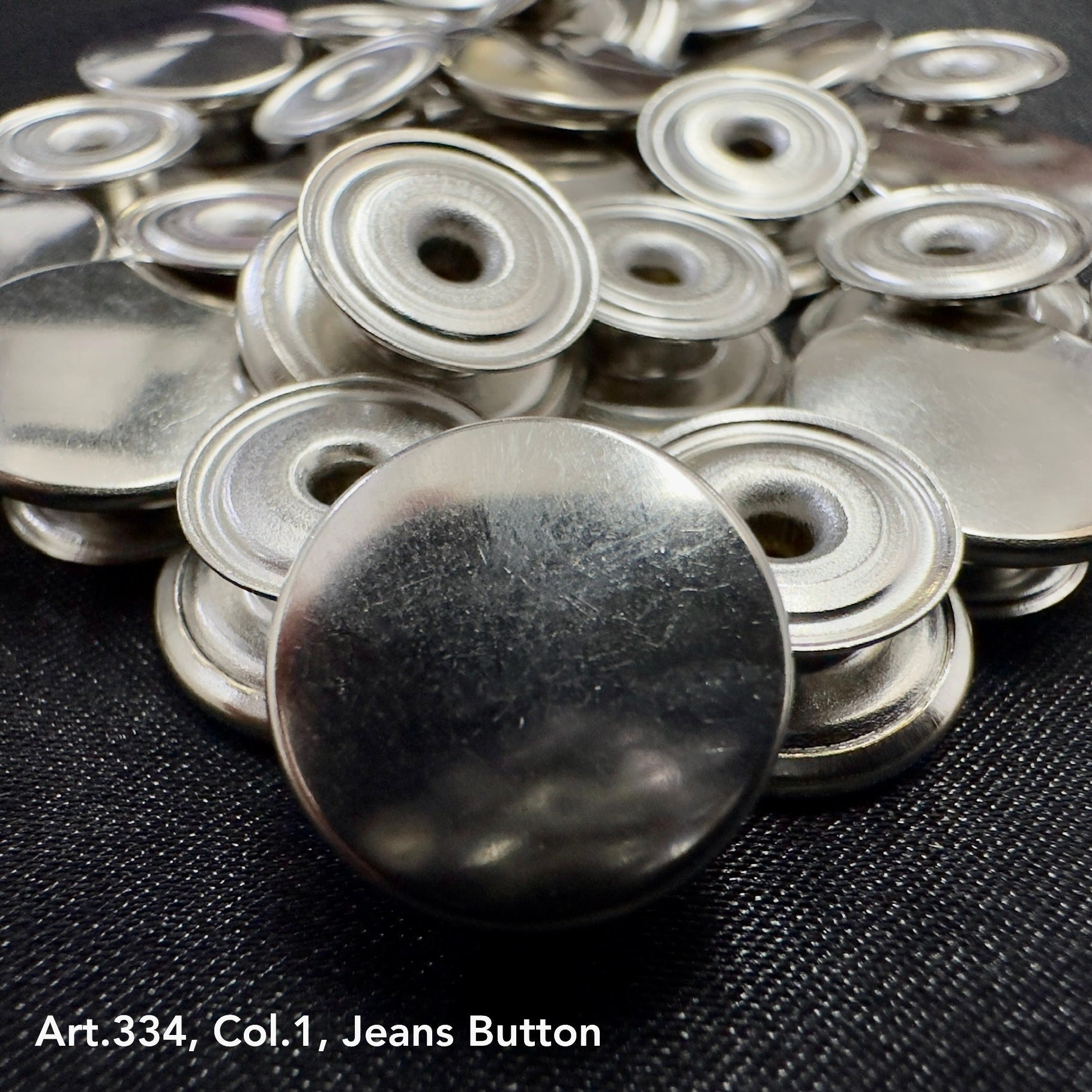 Shiny metal jean buttons for sewing displayed in a pile, ideal for DIY fashion projects