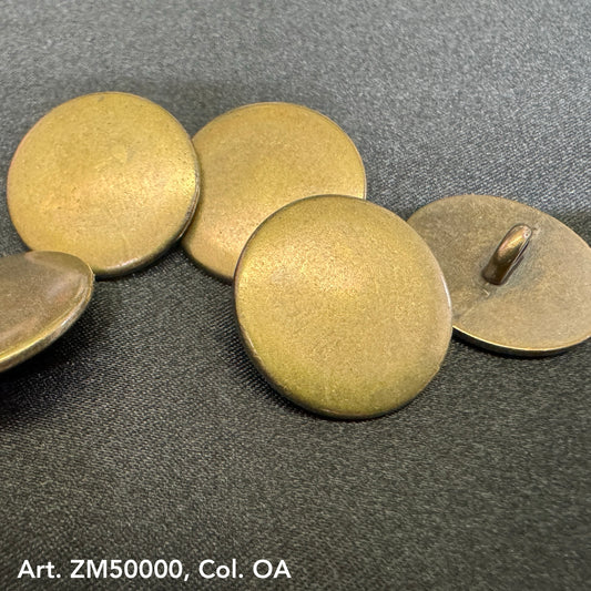Round antique brass metal shank buttons from Buttonology Inc on a dark fabric background