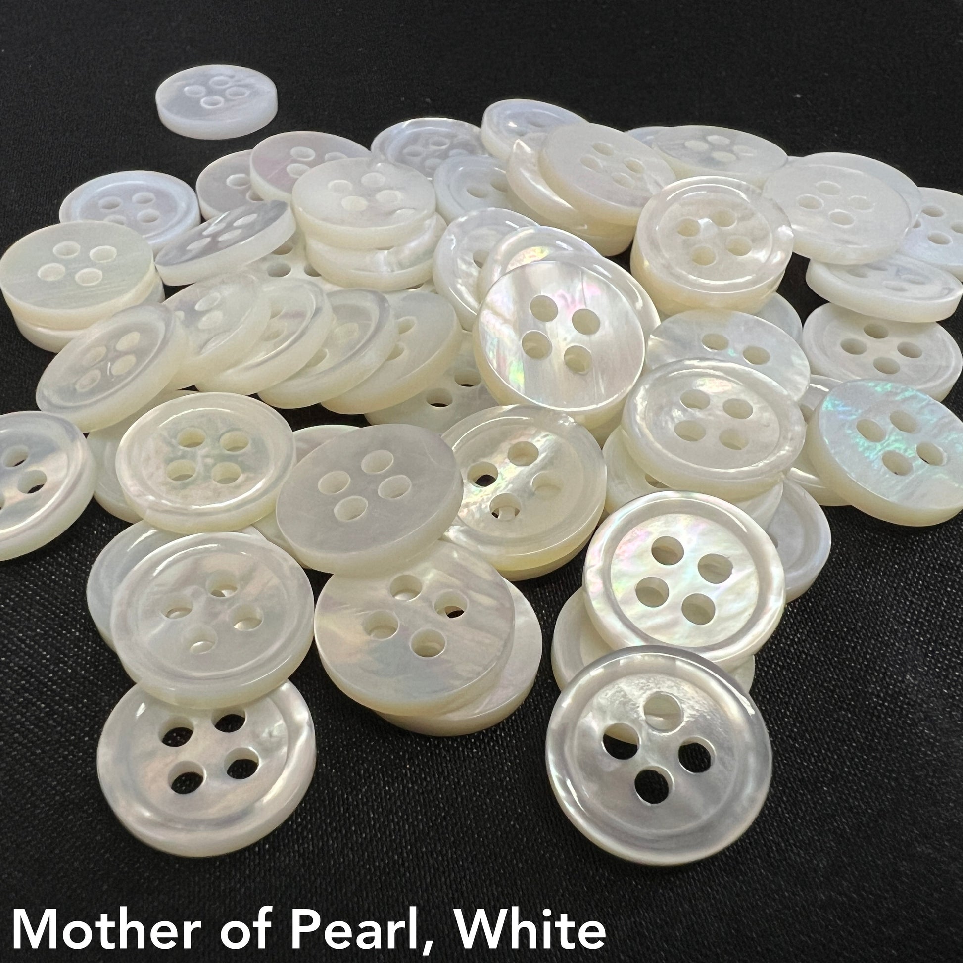 Close-up of white mother of pearl buttons by Buttonology Inc with four holes on black background