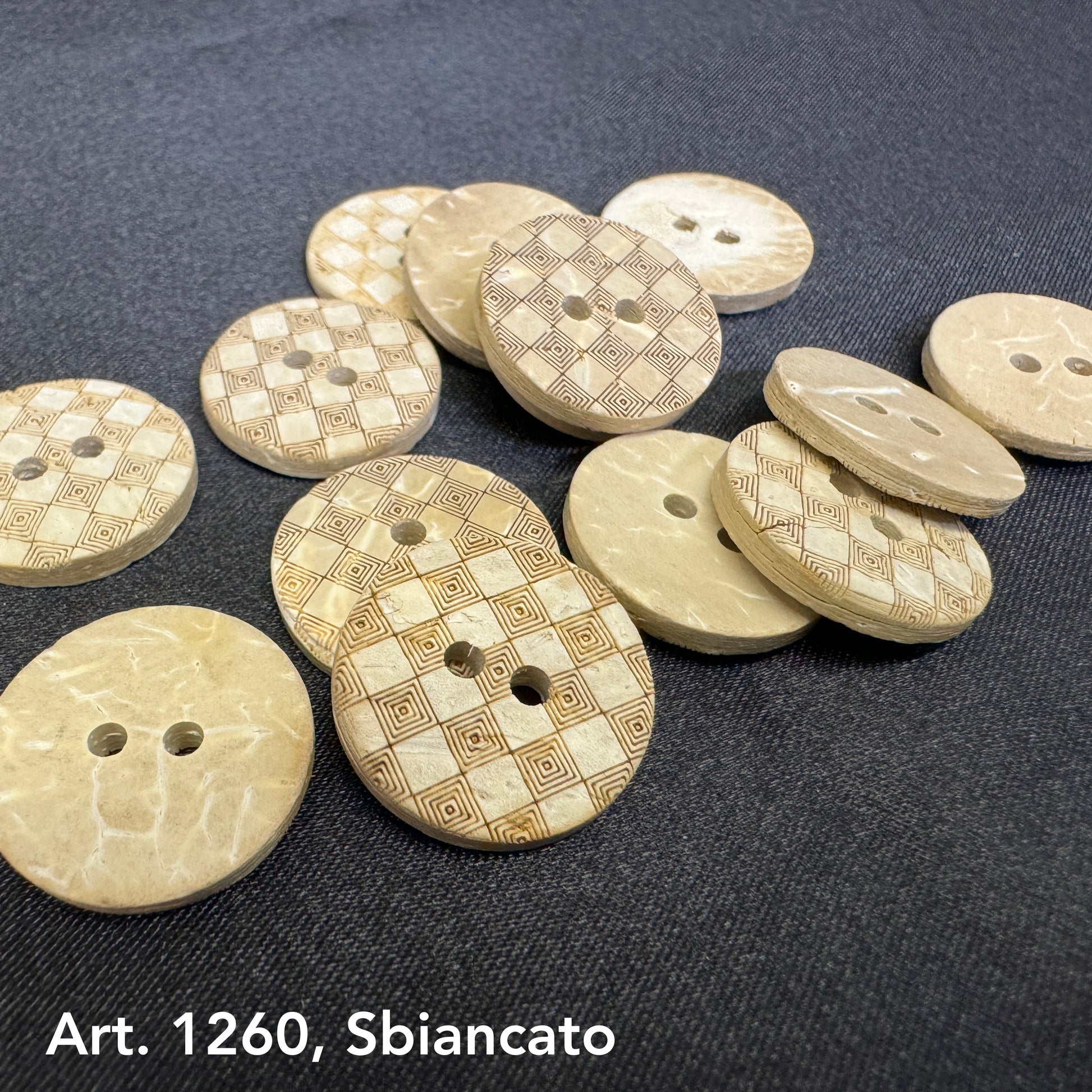 Natural coconut buttons by Buttonology Inc with engraved geometric patterns on a dark fabric background