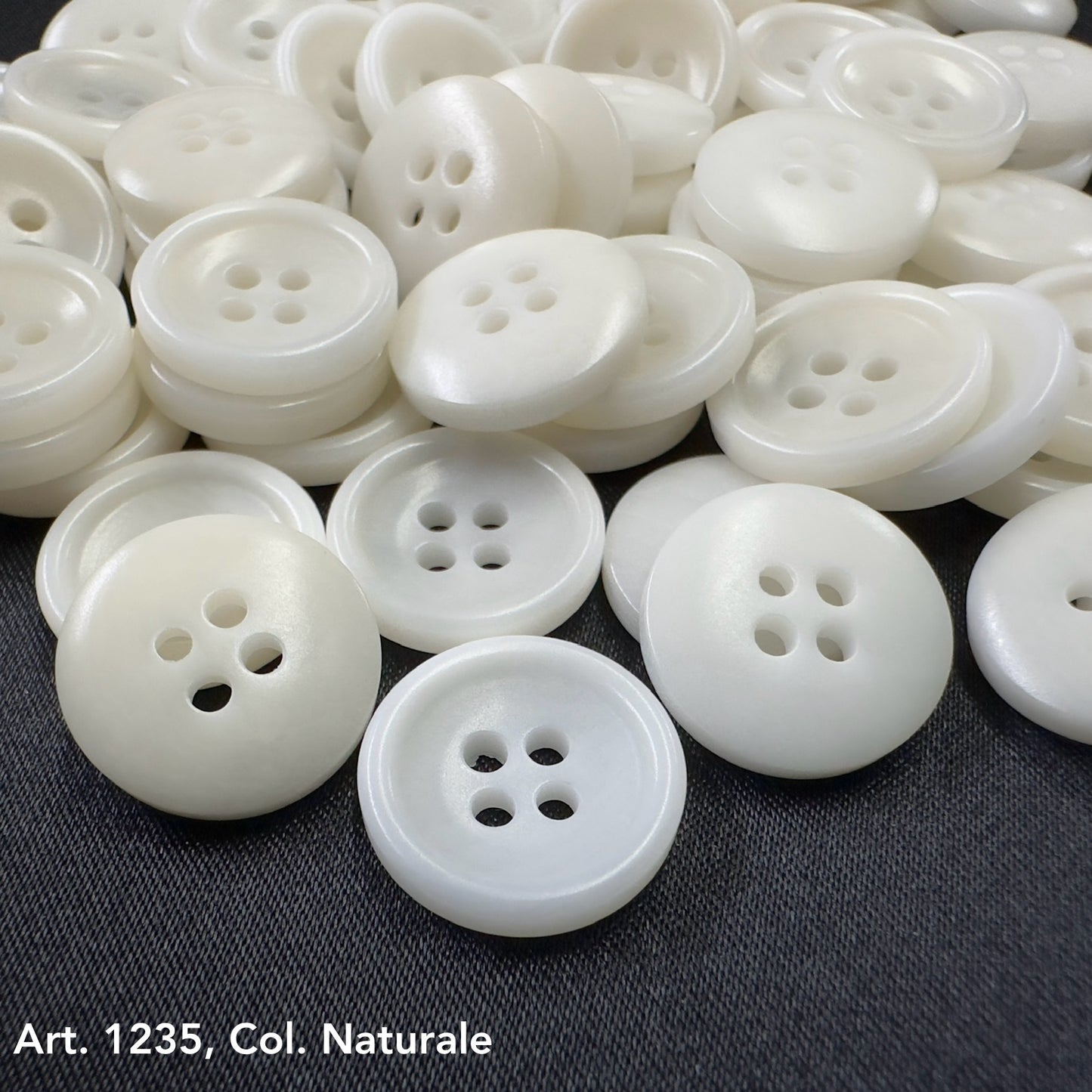 White Sustainable Sewing Buttons with four holes from Buttonology Inc. on a dark fabric background