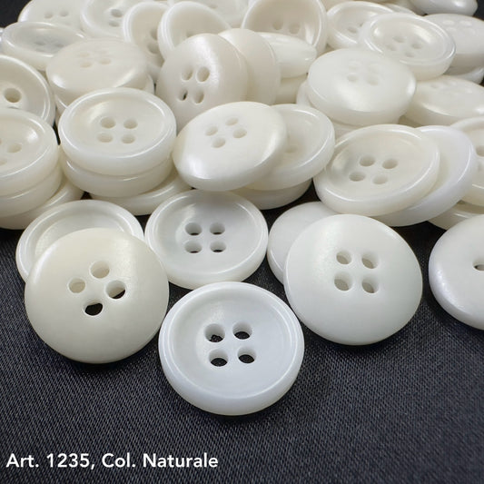 White Sustainable Sewing Buttons with four holes from Buttonology Inc. on a dark fabric background